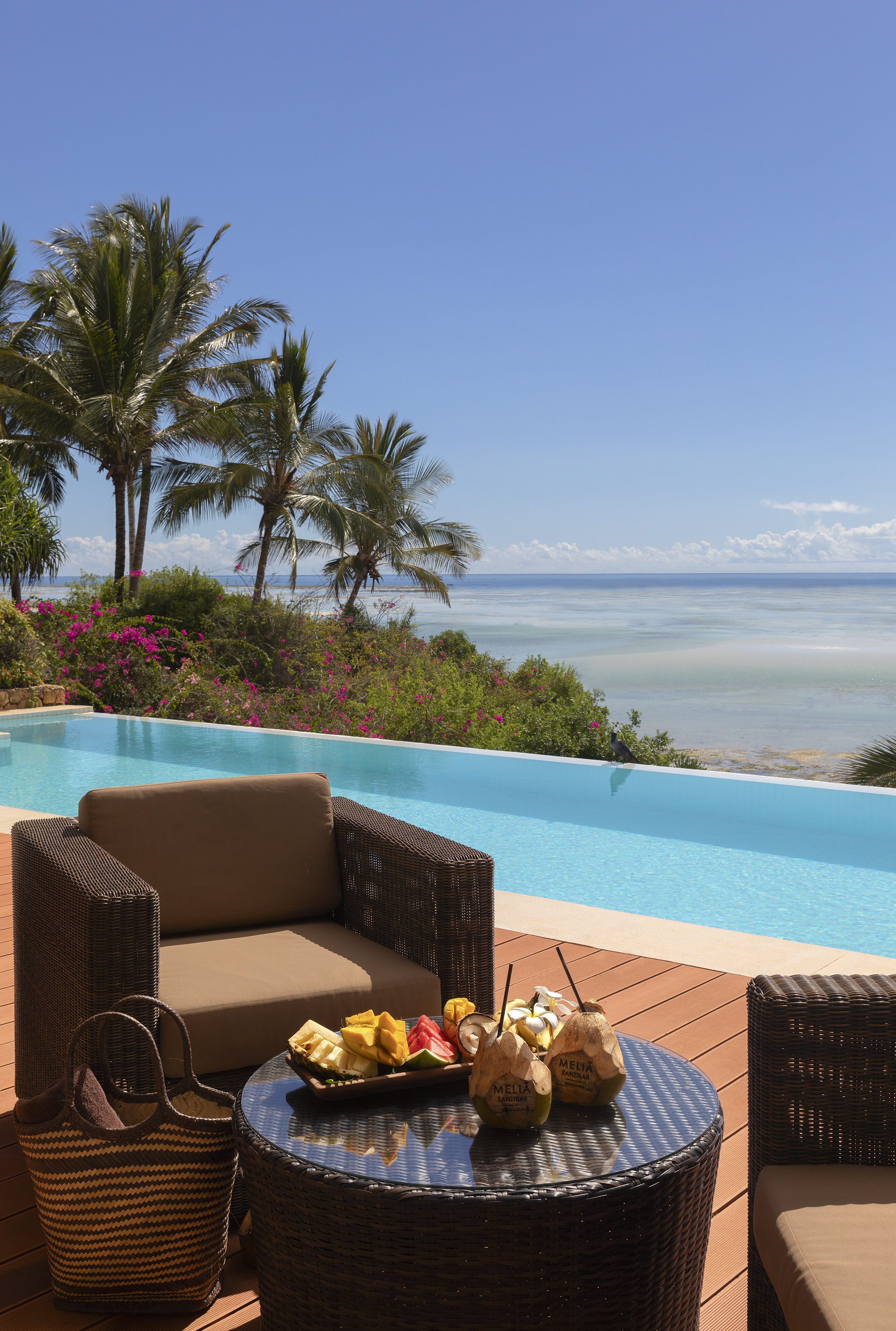 a pool with a table and chairs and a beach view