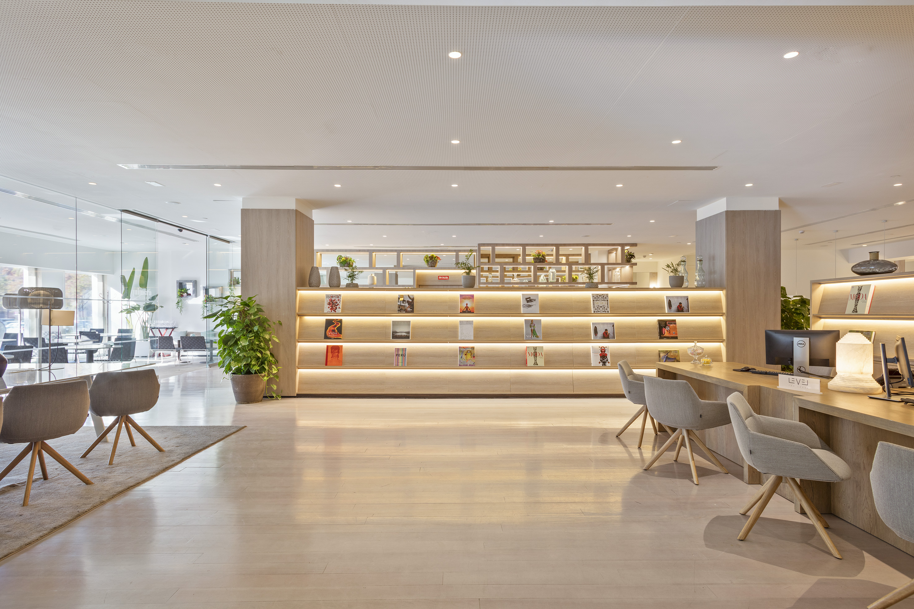 Modern hotel lobby with illuminated wooden bookshelves, reception, and lounge.