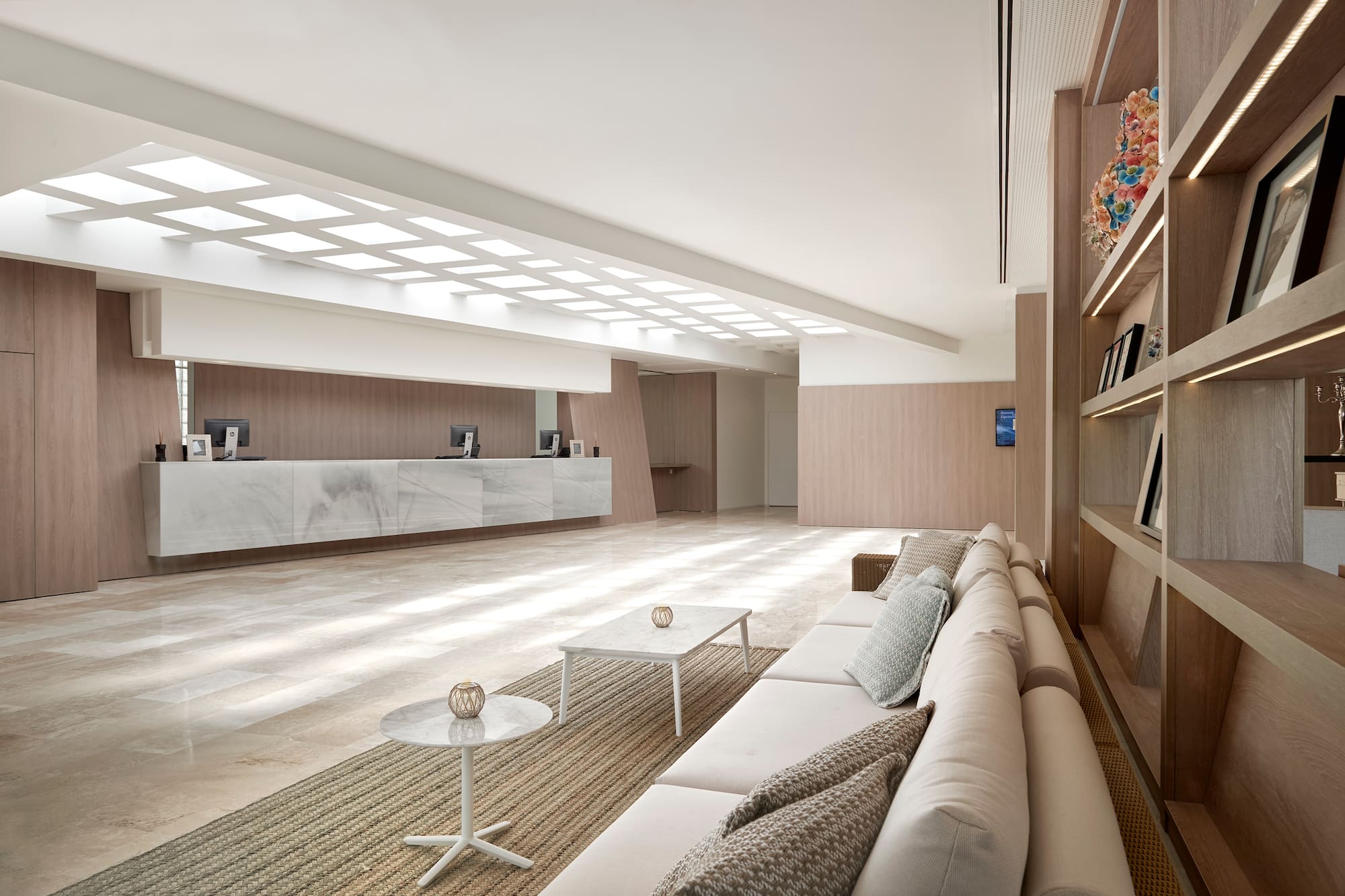 Modern hotel lobby with marble reception, plush sofa, and wood paneling.