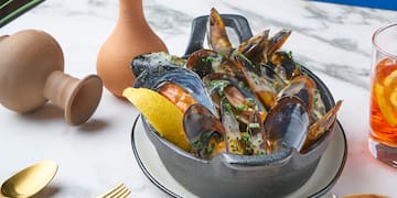 a plate of mussels and lemons on a marble table