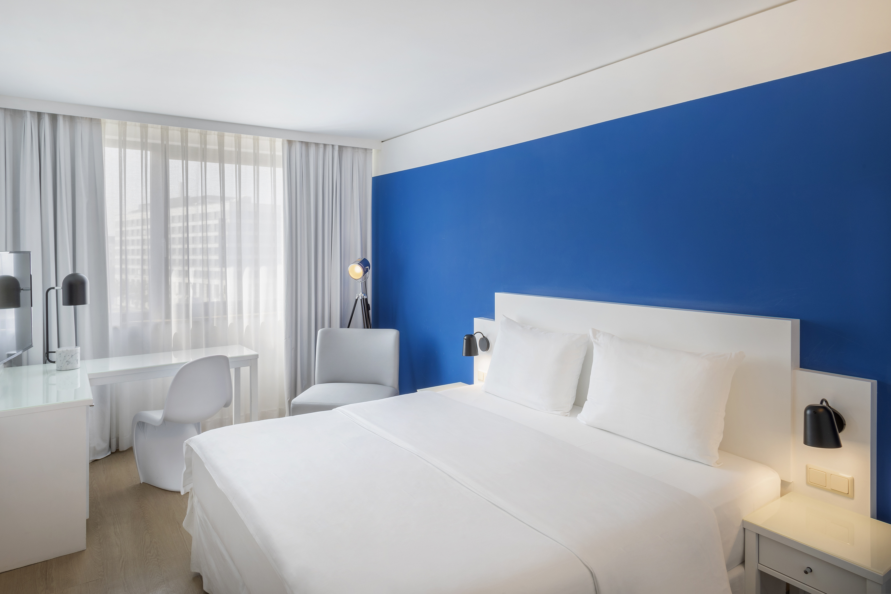 a bed with white sheets and a blue wall