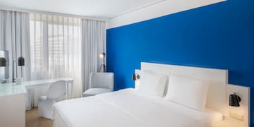 a bed with white sheets and a blue wall
