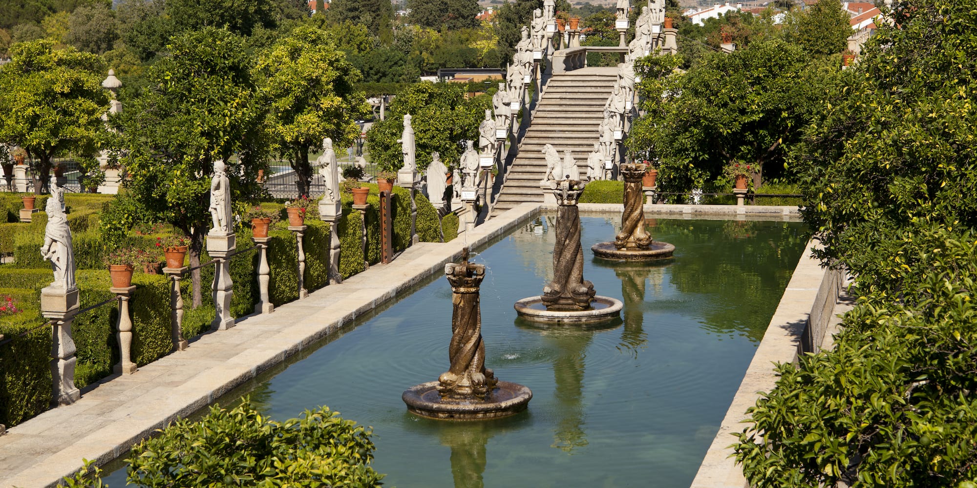 a water fountain with statues in the middle of a garden