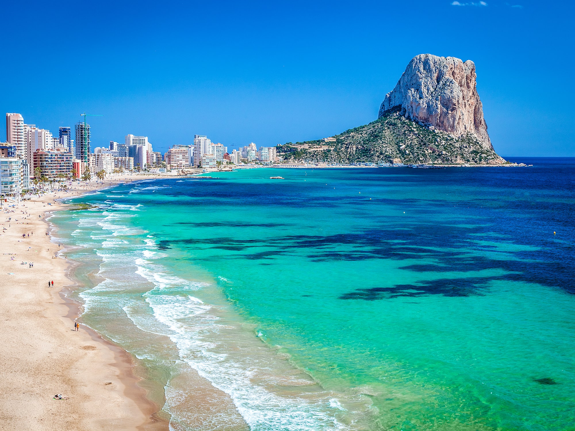 Calpe, Spain: Penon de Ifach, sandy beach, turquoise sea, and city skyline.