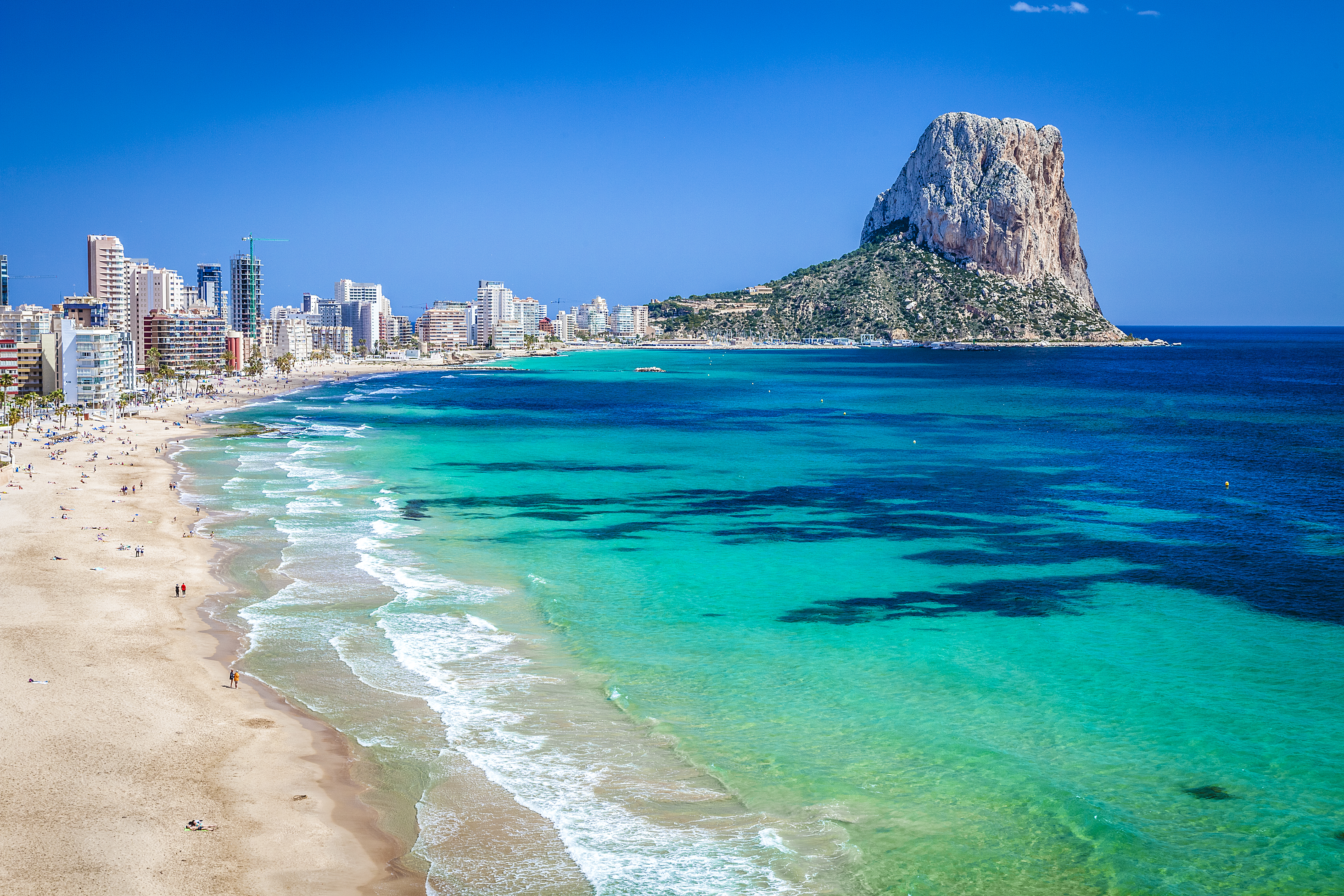 Calpe, Spain: Penon de Ifach, sandy beach, turquoise sea, and city skyline.