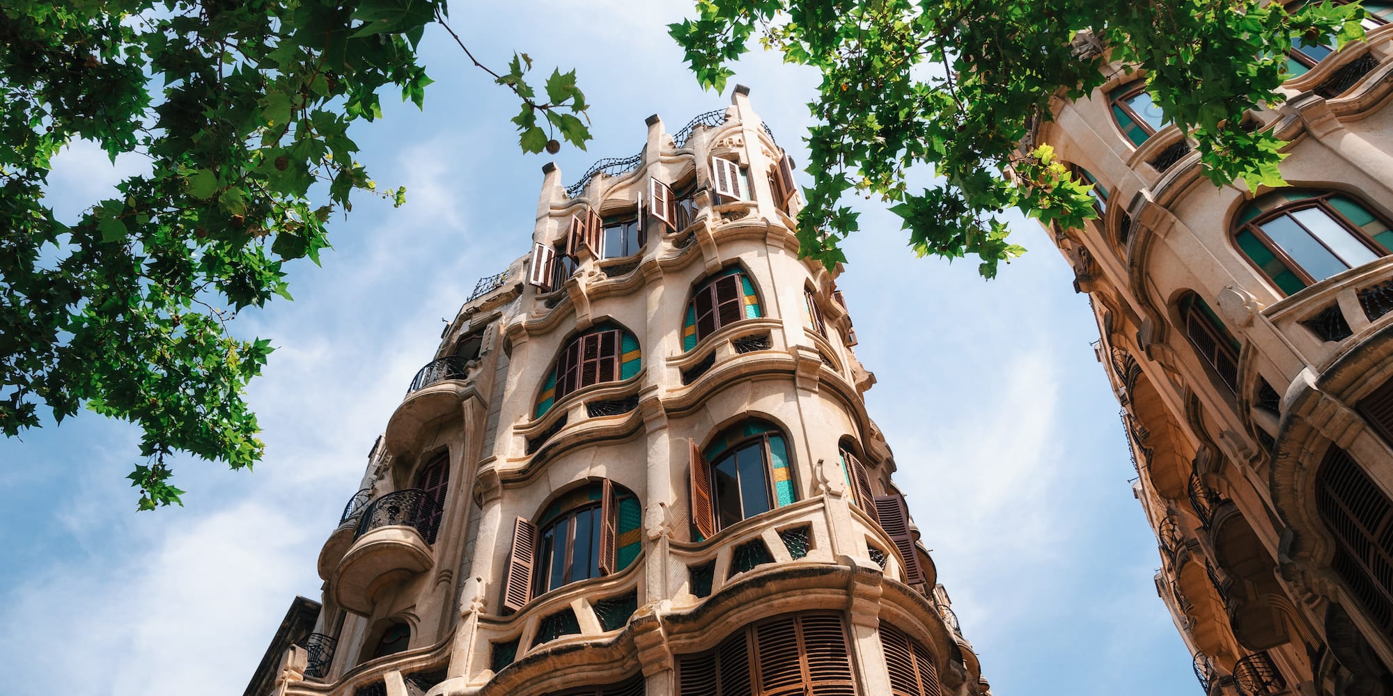 Arquitectura modernista, edificio curvo con balcones y persianas, hojas.
