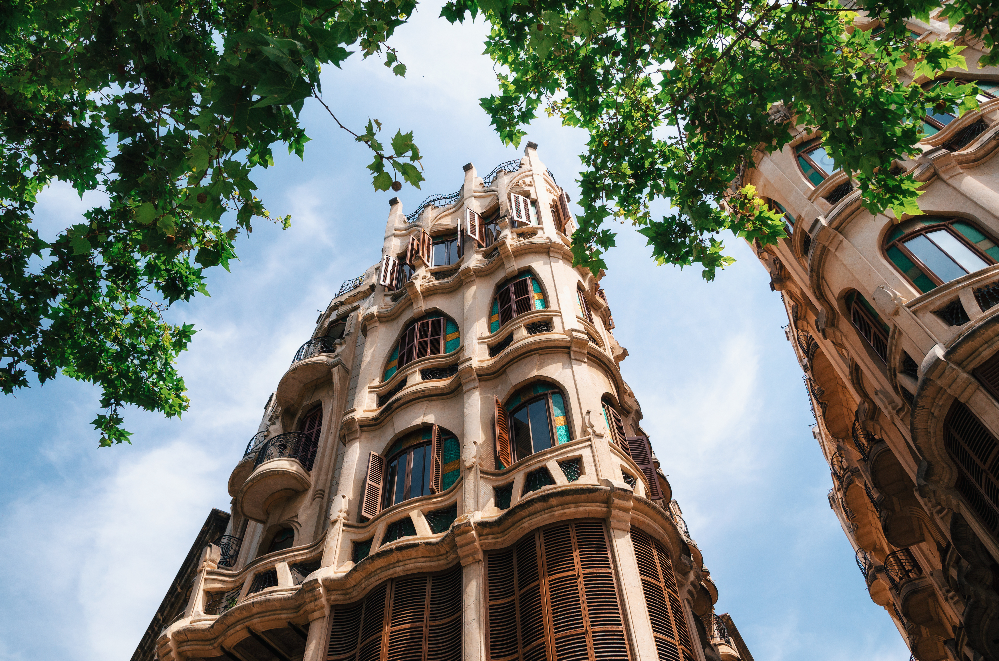 Arquitectura modernista, edificio curvo con balcones y persianas, hojas.