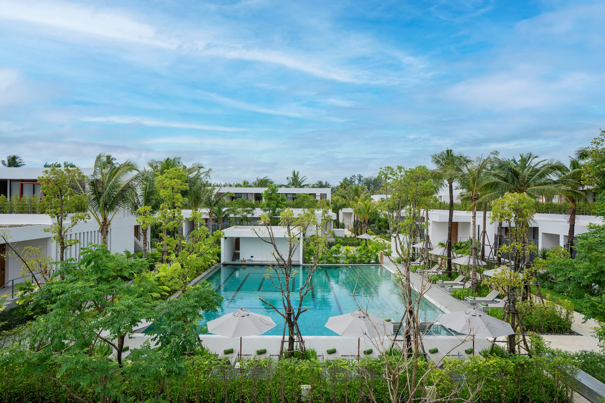 Luxury resort pool, modern buildings, tropical palm trees.