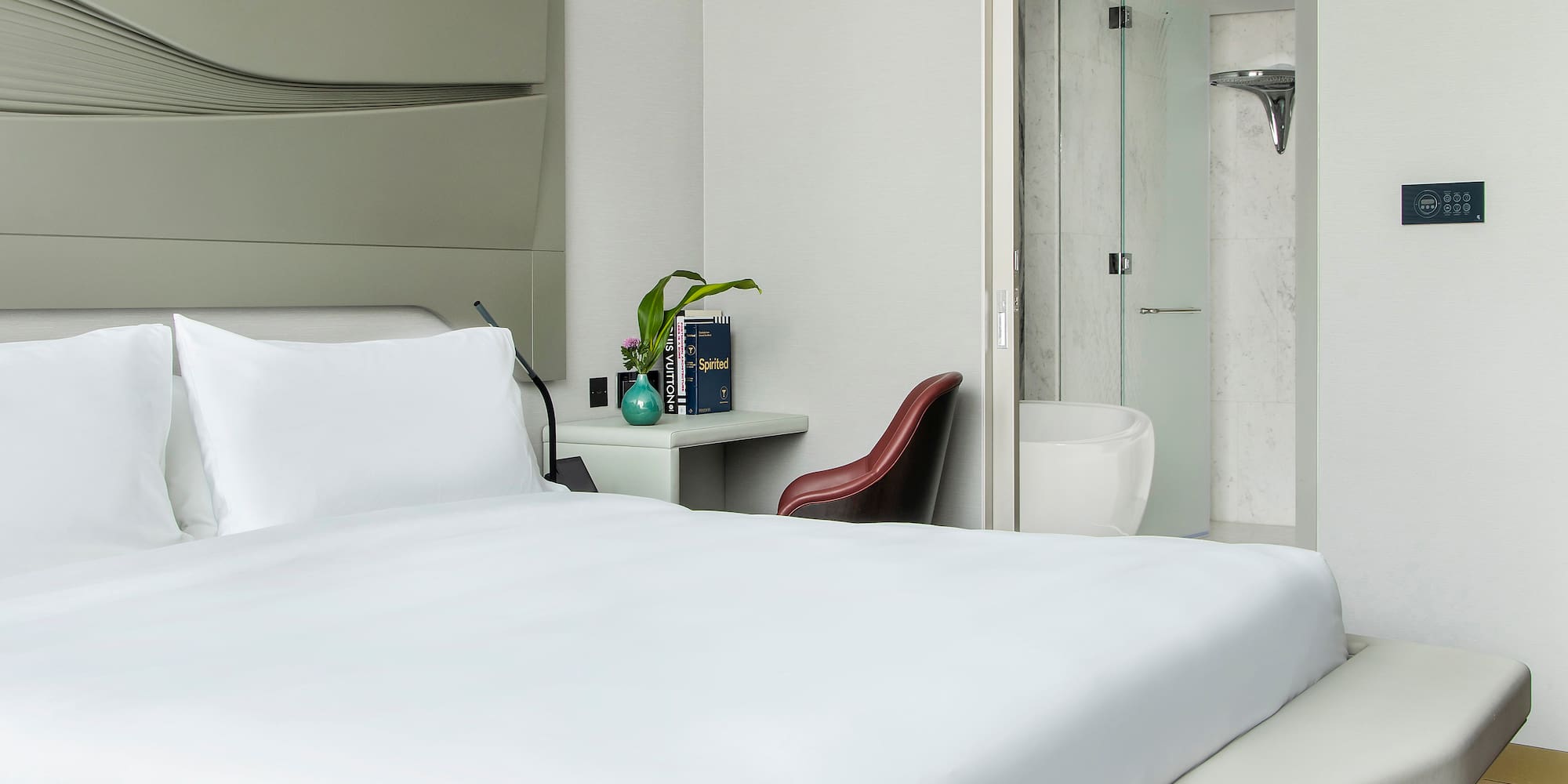 a bed with white sheets and a vase on the side