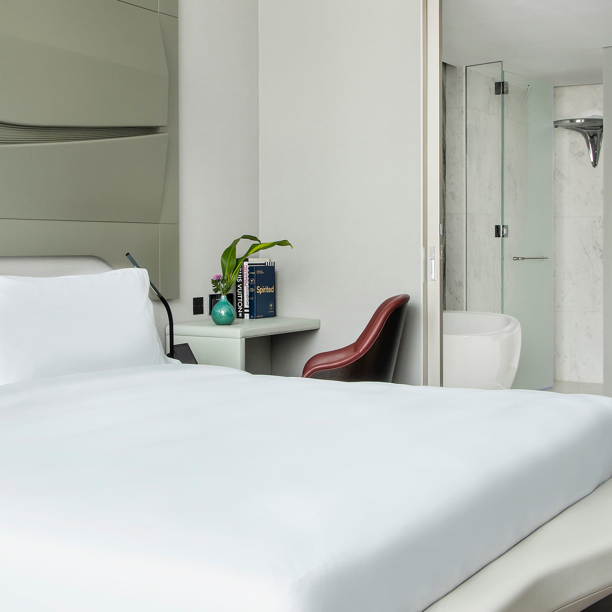 a bed with white sheets and a vase on the side