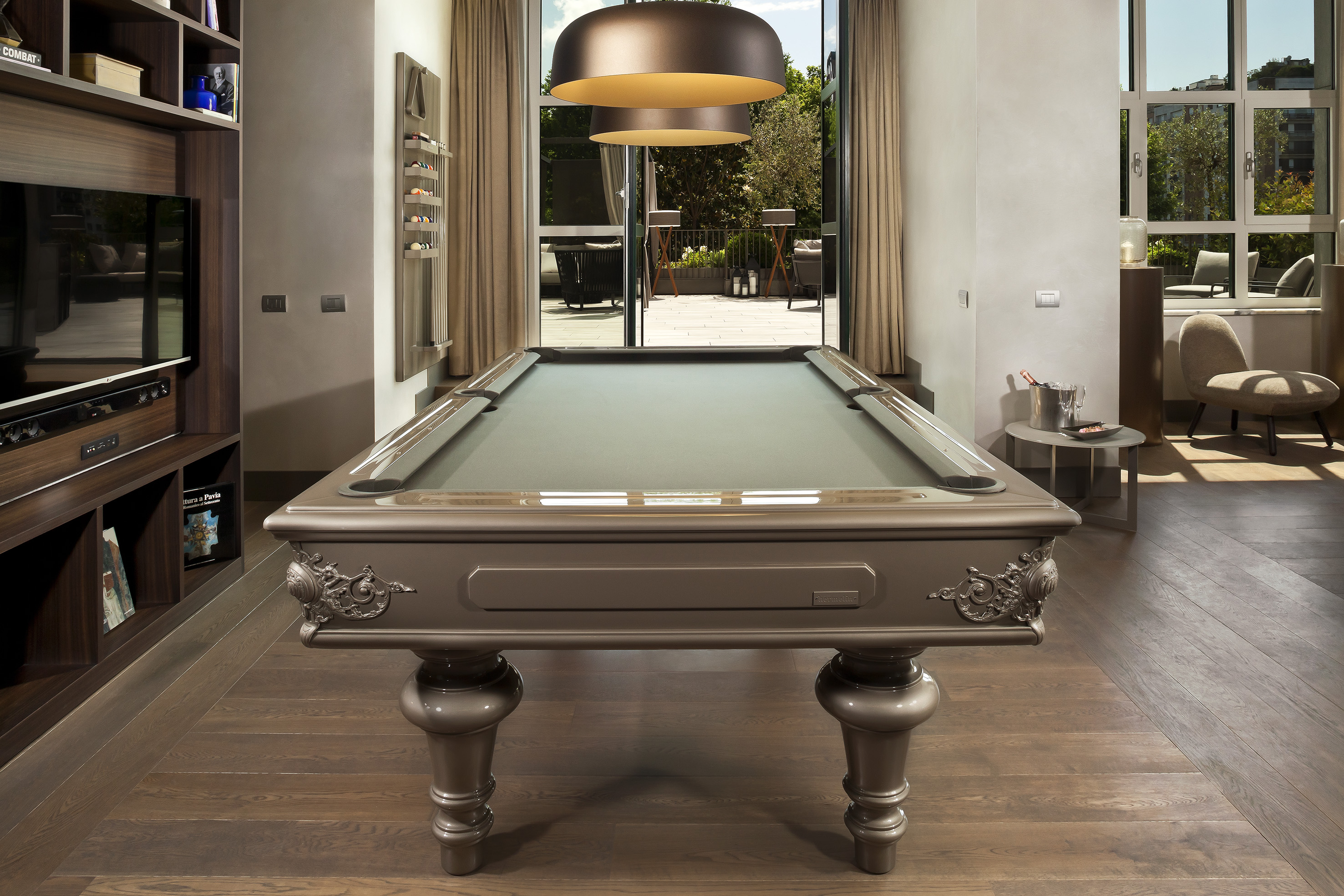Ornate modern billiard table in a luxury game room with large windows.