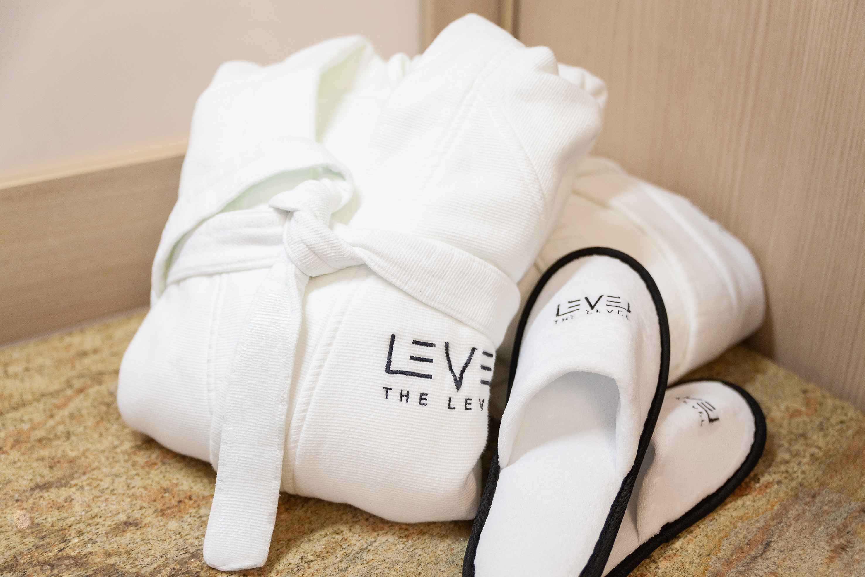 White luxury hotel bathrobe and slippers with 'THE LEVEL' branding.