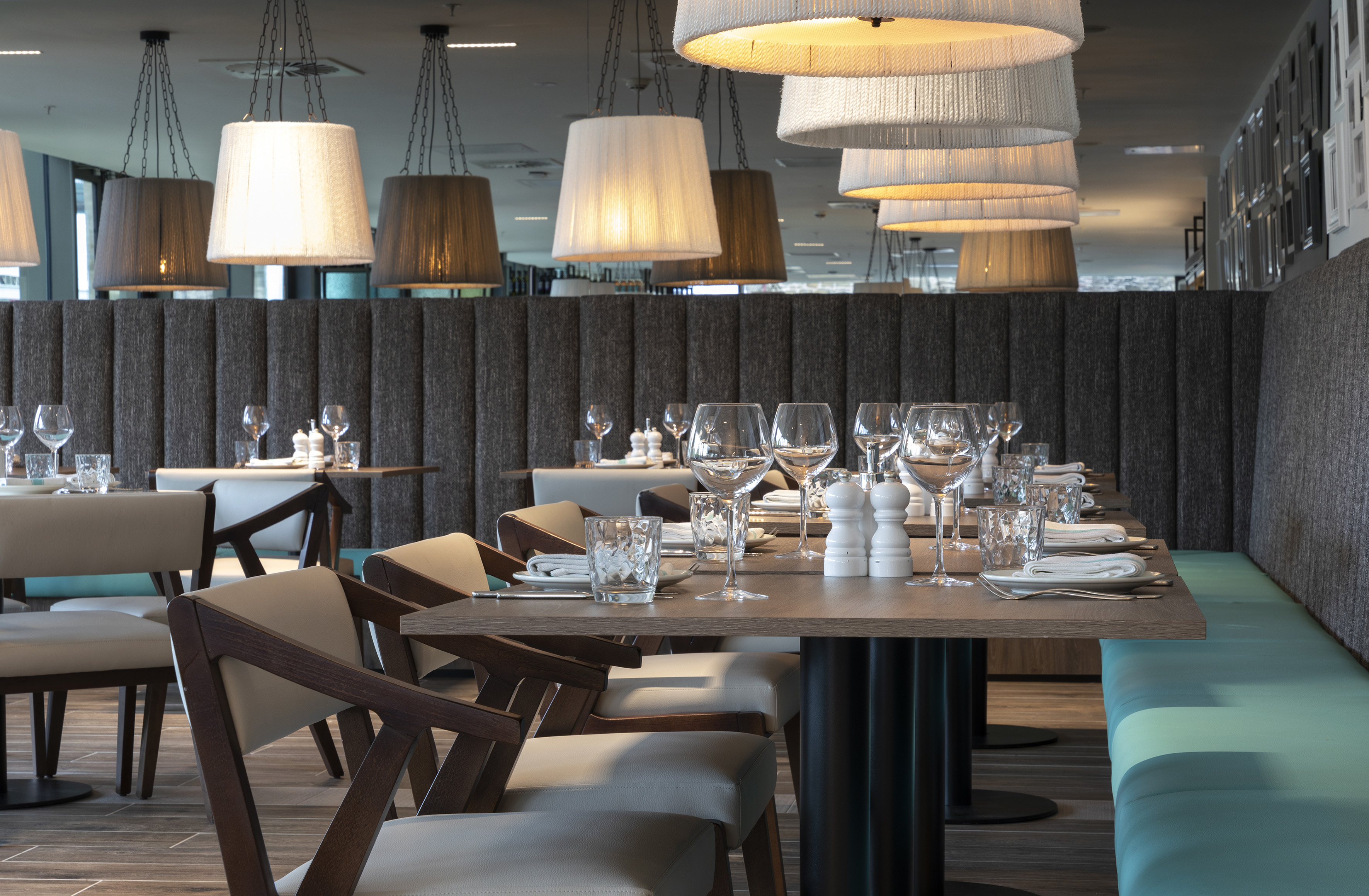 Modern restaurant dining tables, pendant lights, and turquoise booth seating.