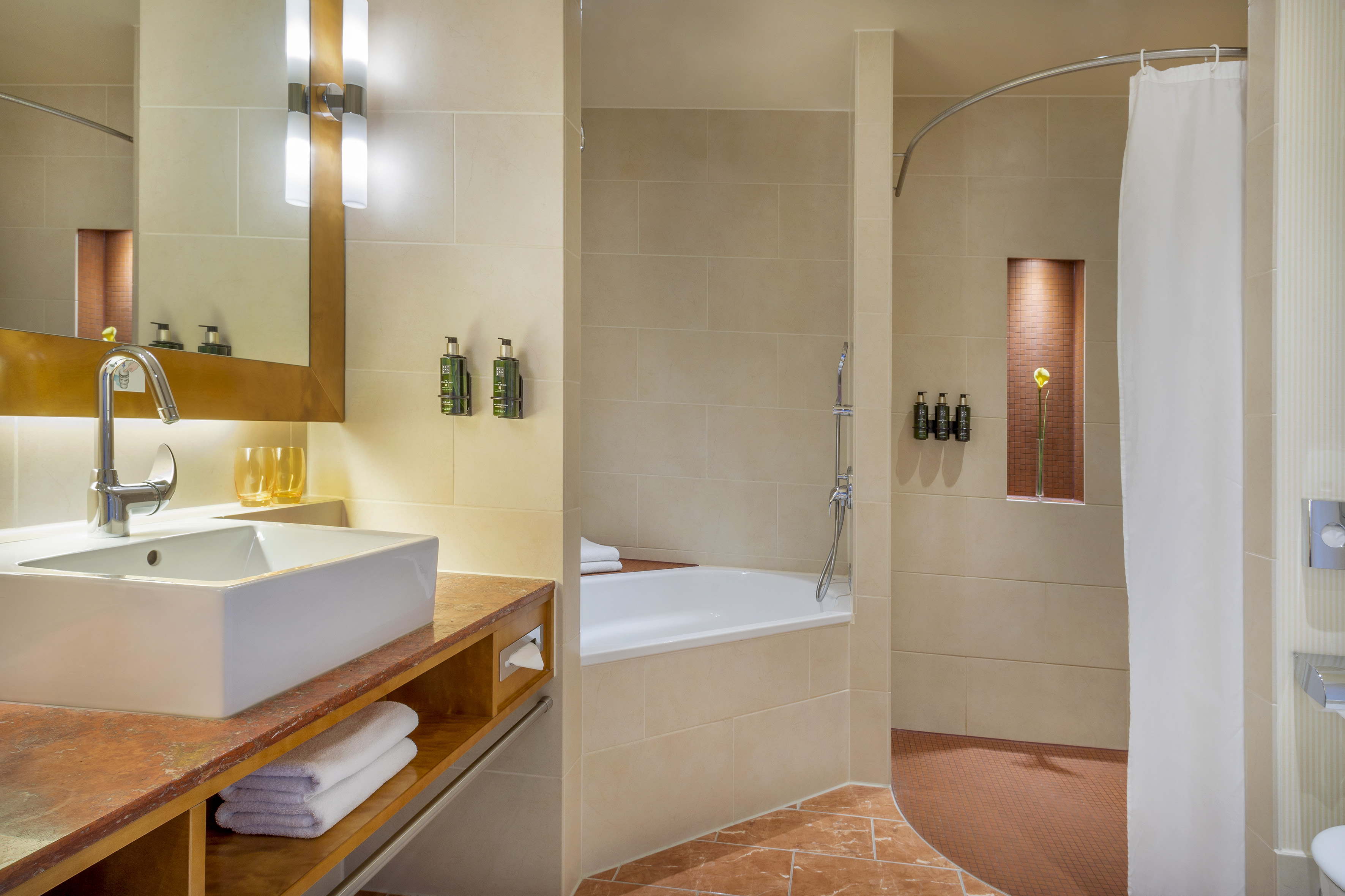 Modern tiled bathroom with vessel sink, mirror, bathtub, and shower.