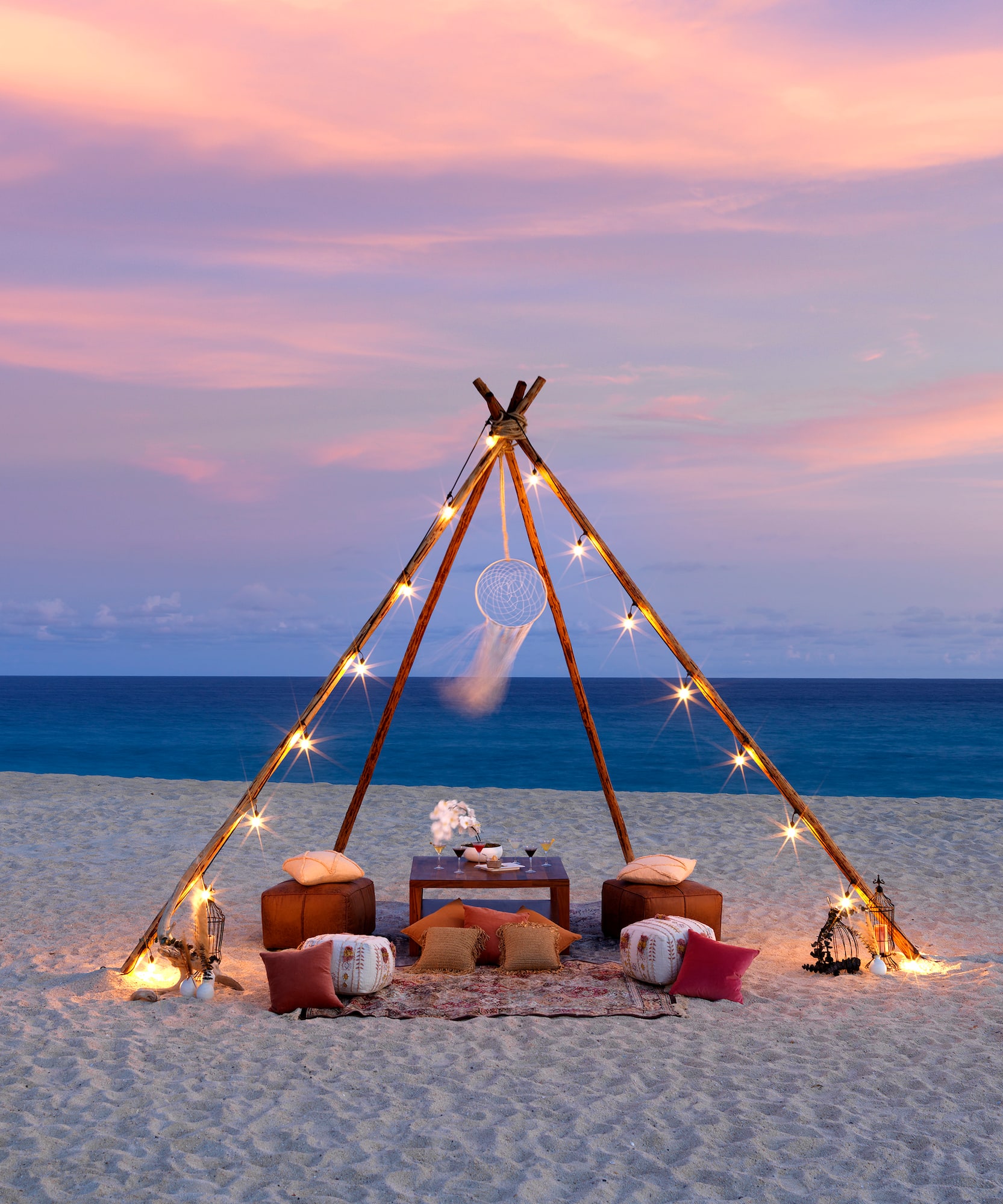 a tent on a beach with lights and a dream catcher