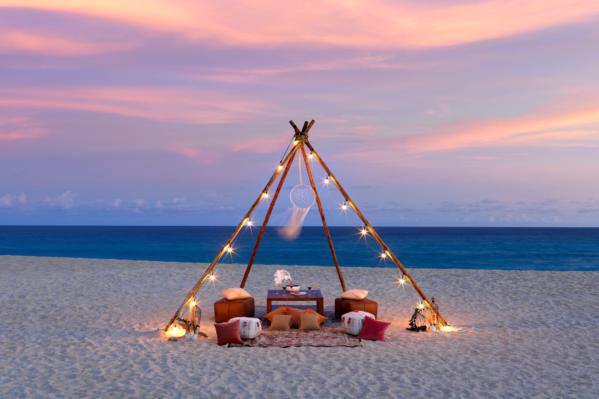 a tent on a beach with lights and a dream catcher
