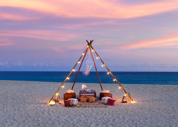 a tent on a beach with lights and a dream catcher