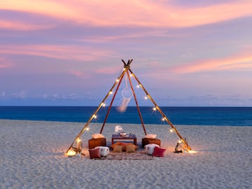 a tent on a beach with lights and a dream catcher