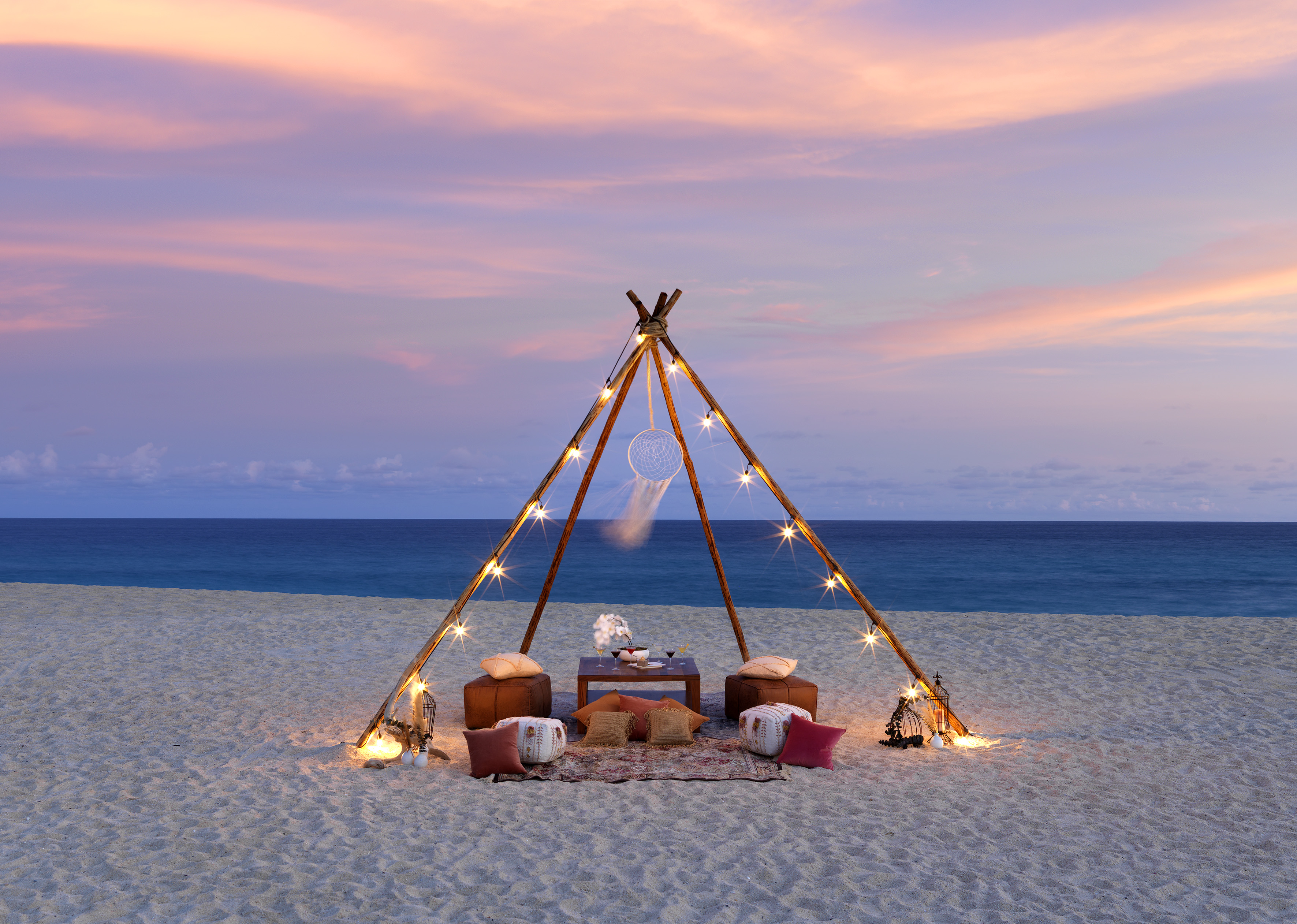 a tent on a beach with lights and a dream catcher