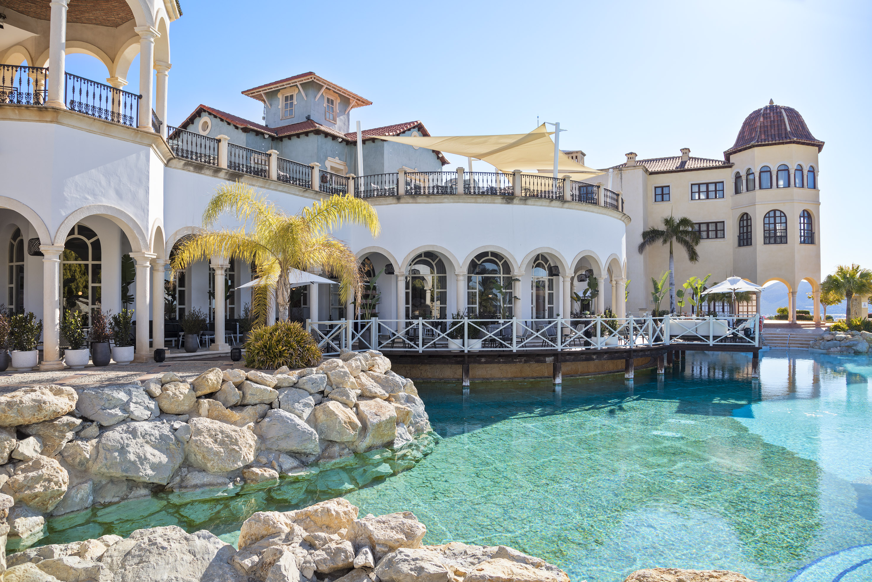 Mediterranean resort with arcaded outdoor dining terrace and turquoise pool.