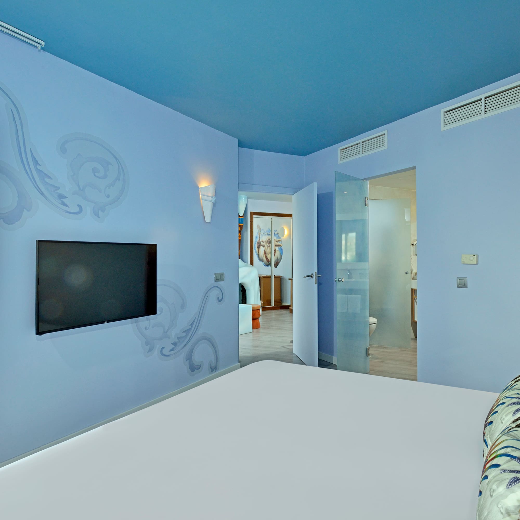 a bedroom with a bed and a television on the wall