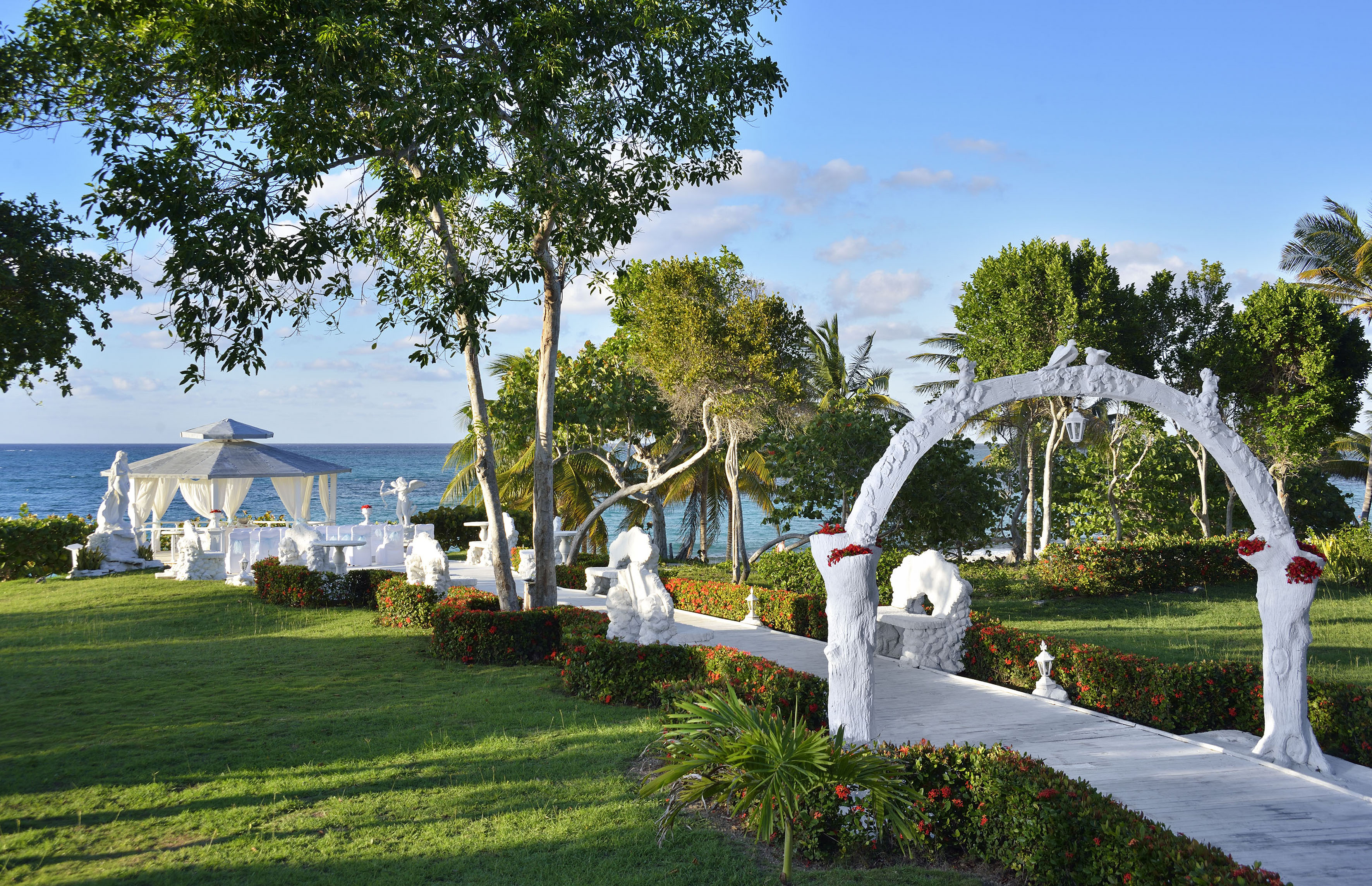 a white walkway with a white structure and trees and a beach
