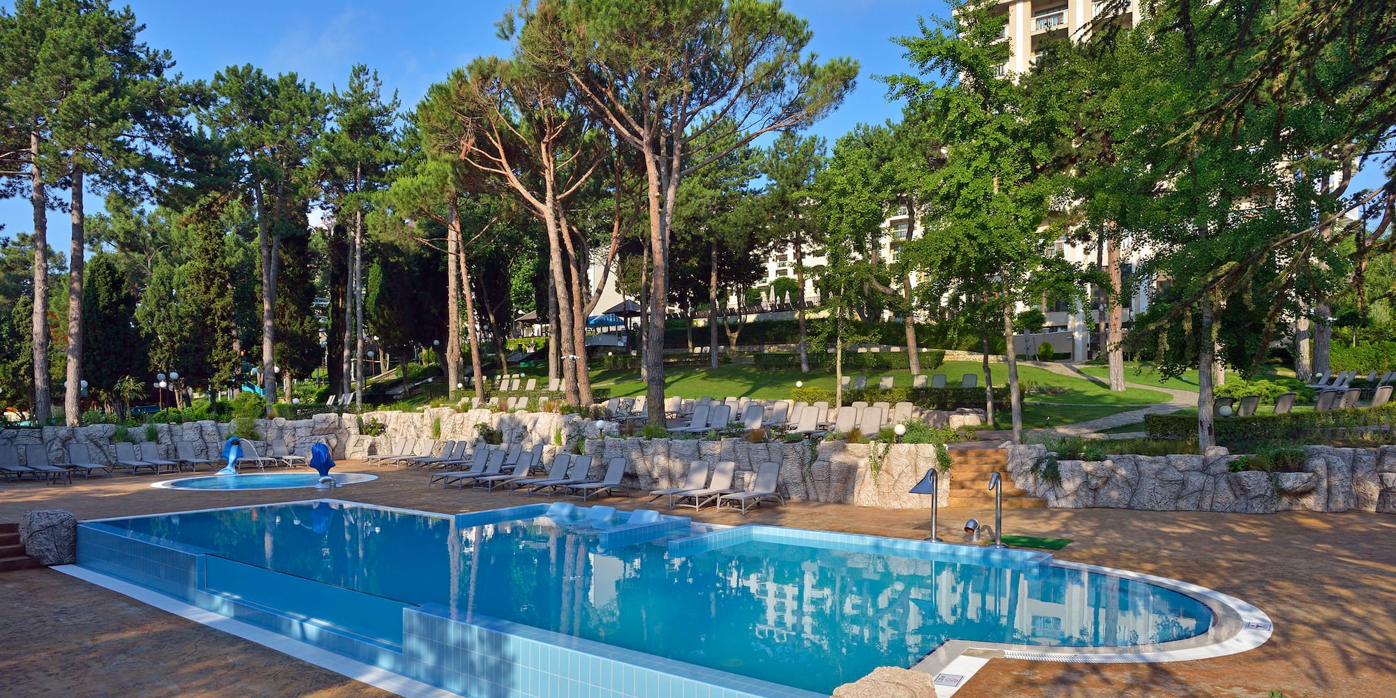 a pool with chairs and trees in the background