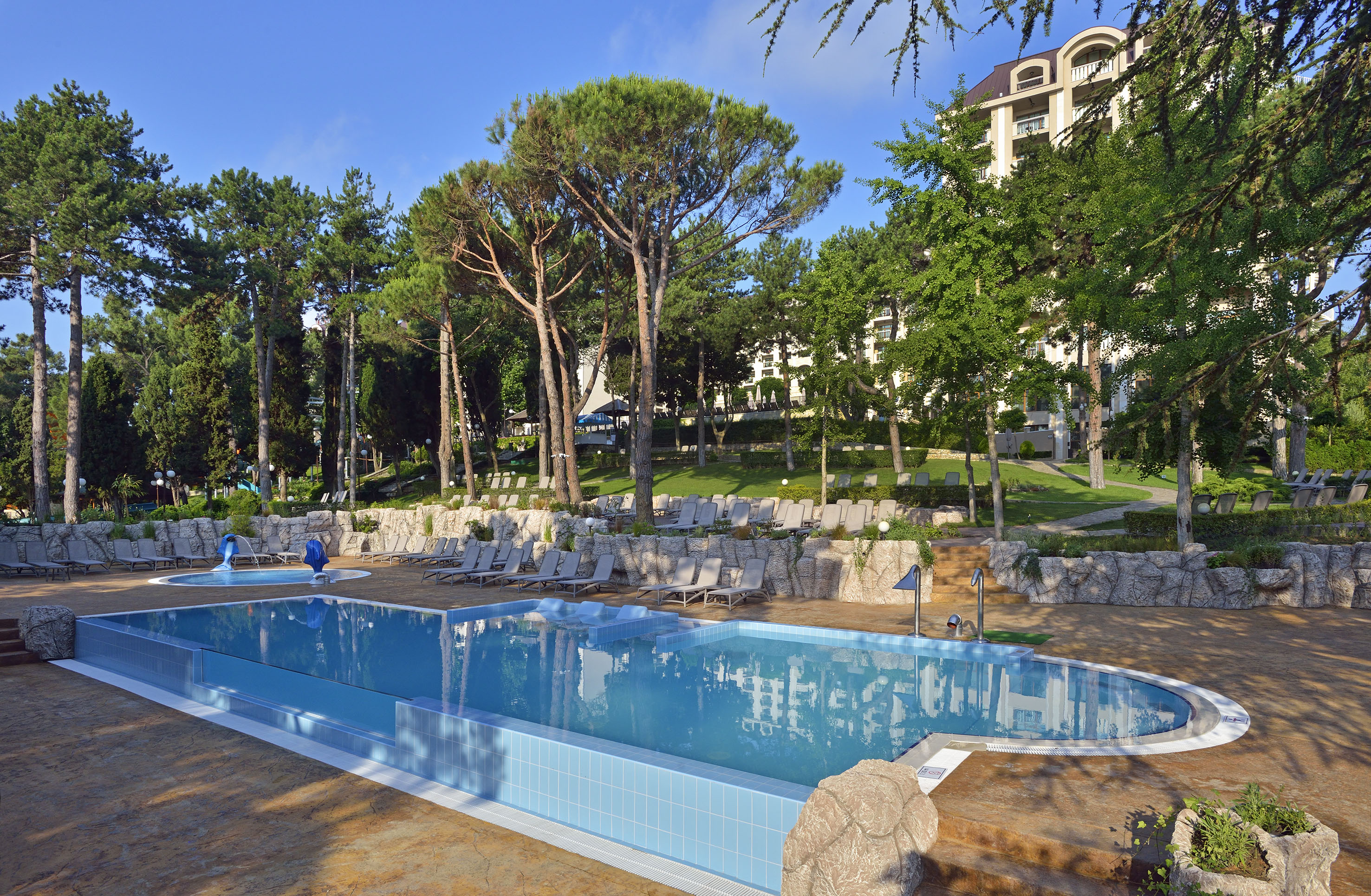 a pool with chairs and trees in the background