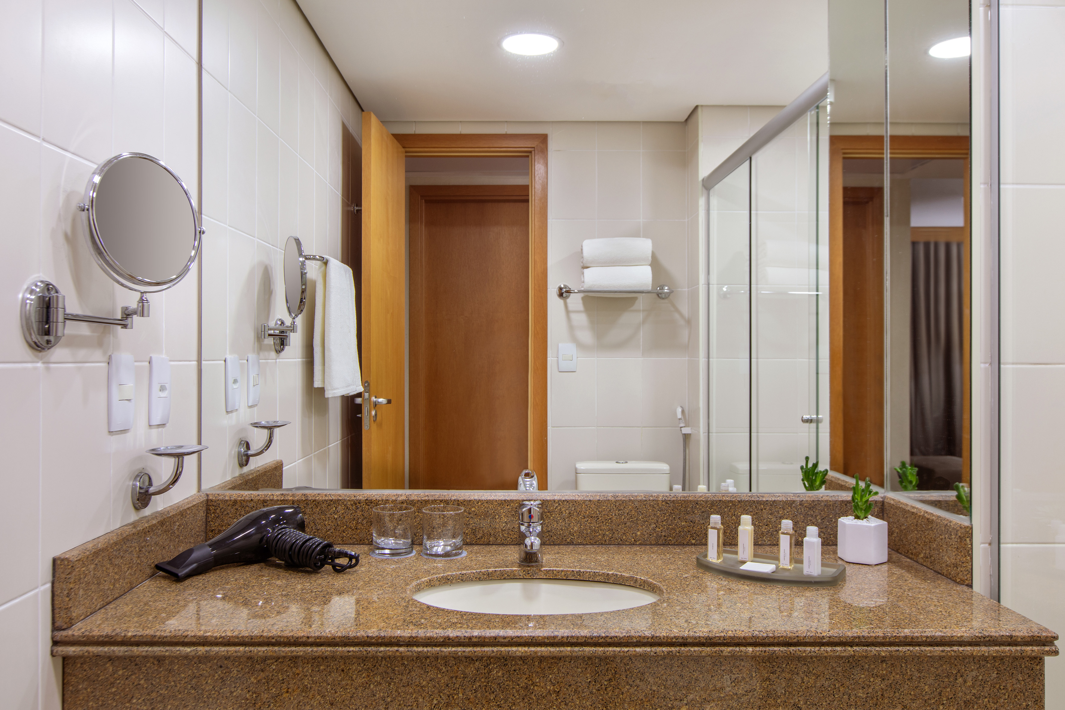 Hotel bathroom with granite vanity, sink, mirror, and hairdryer.