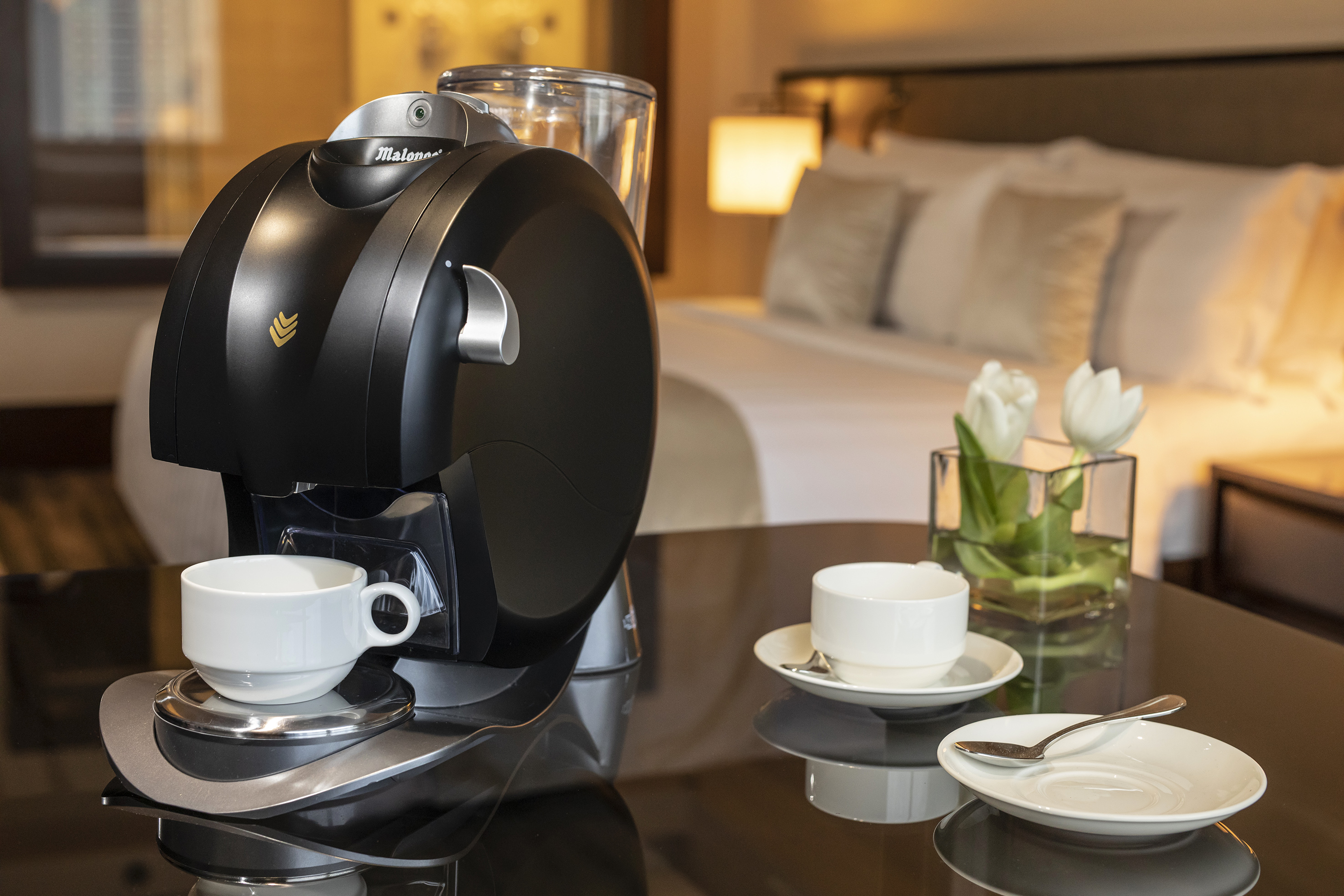 Malongo coffee machine with white cups and tulips in a hotel room.