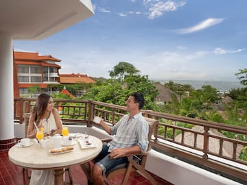 a man and woman sitting at a table with food on a balcony
