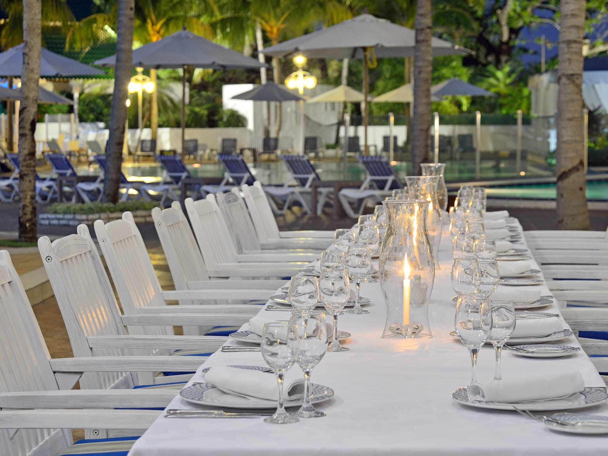 a long table with white chairs and glasses on it
