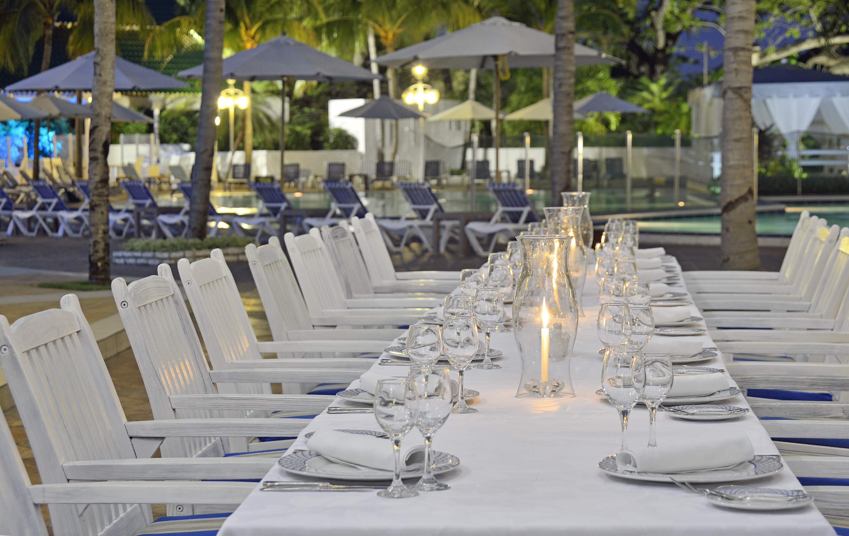 a long table with white chairs and glasses on it