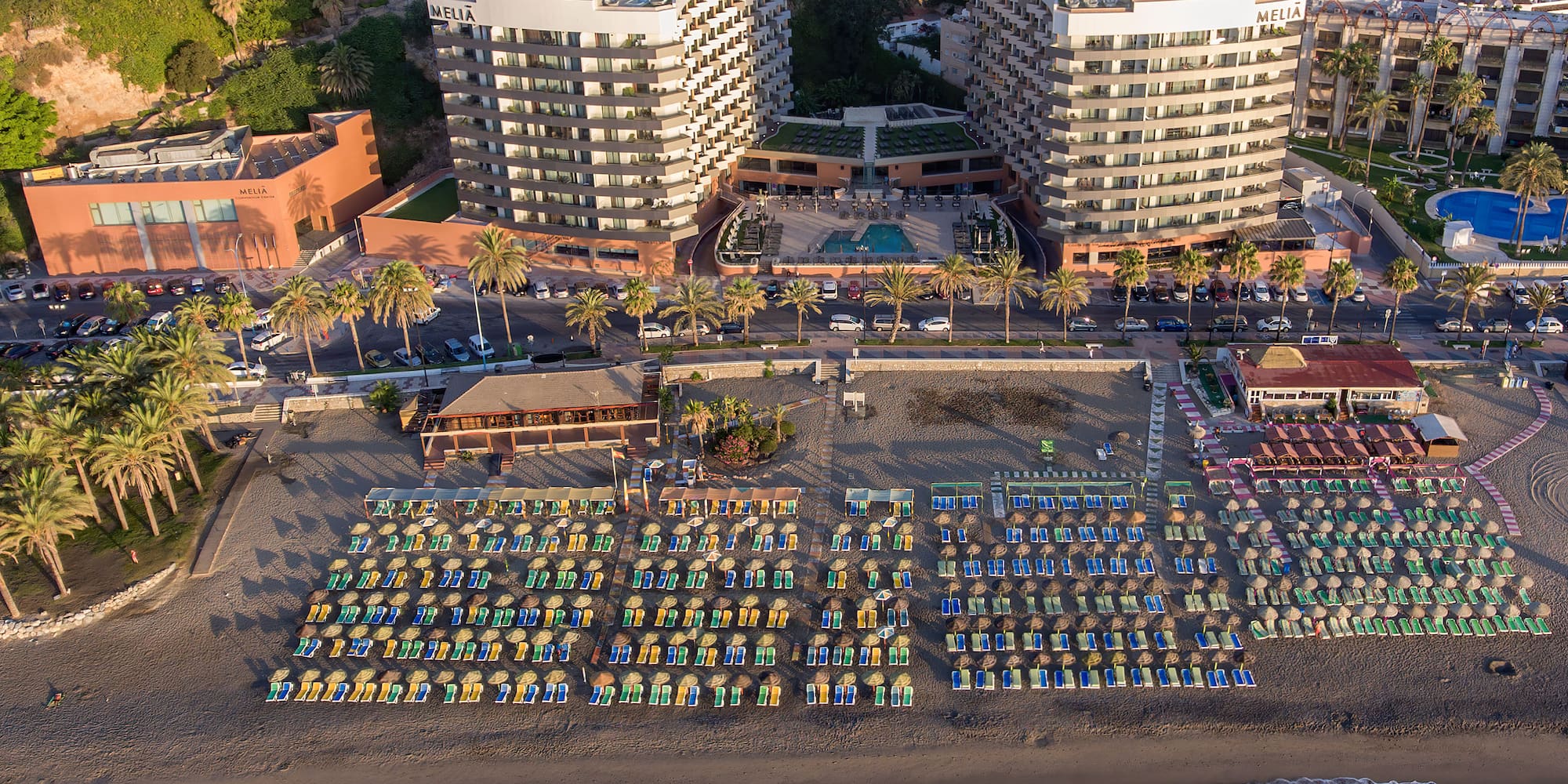 a beach with many chairs and a pool in front of a large building
