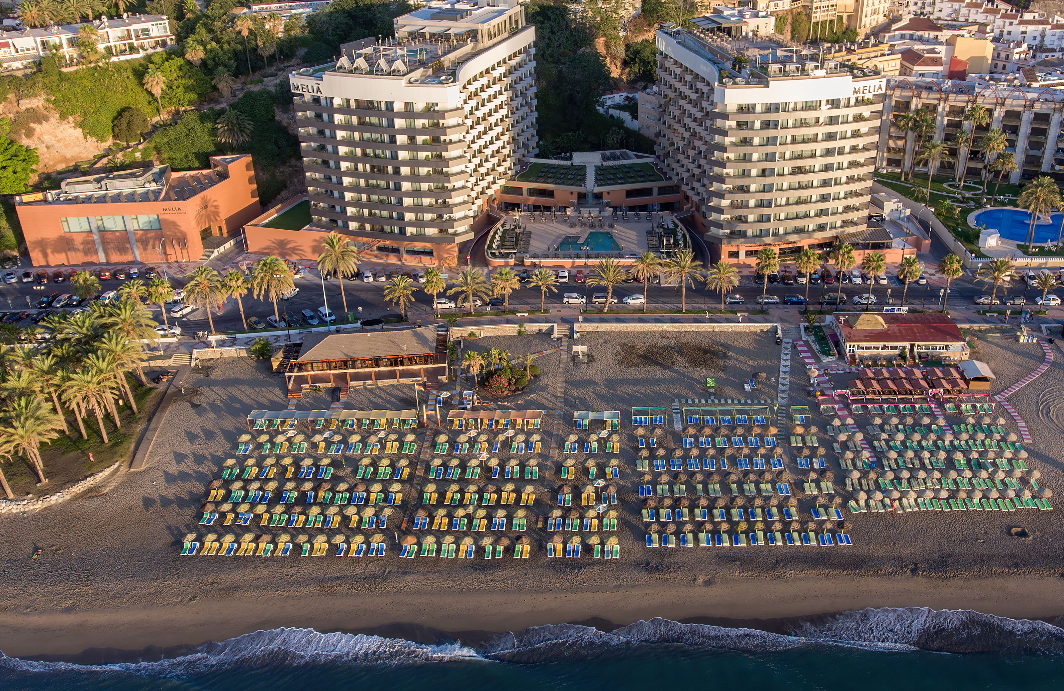 a beach with many chairs and a pool in front of a large building