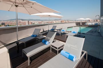 a pool with umbrellas and lounge chairs on a rooftop