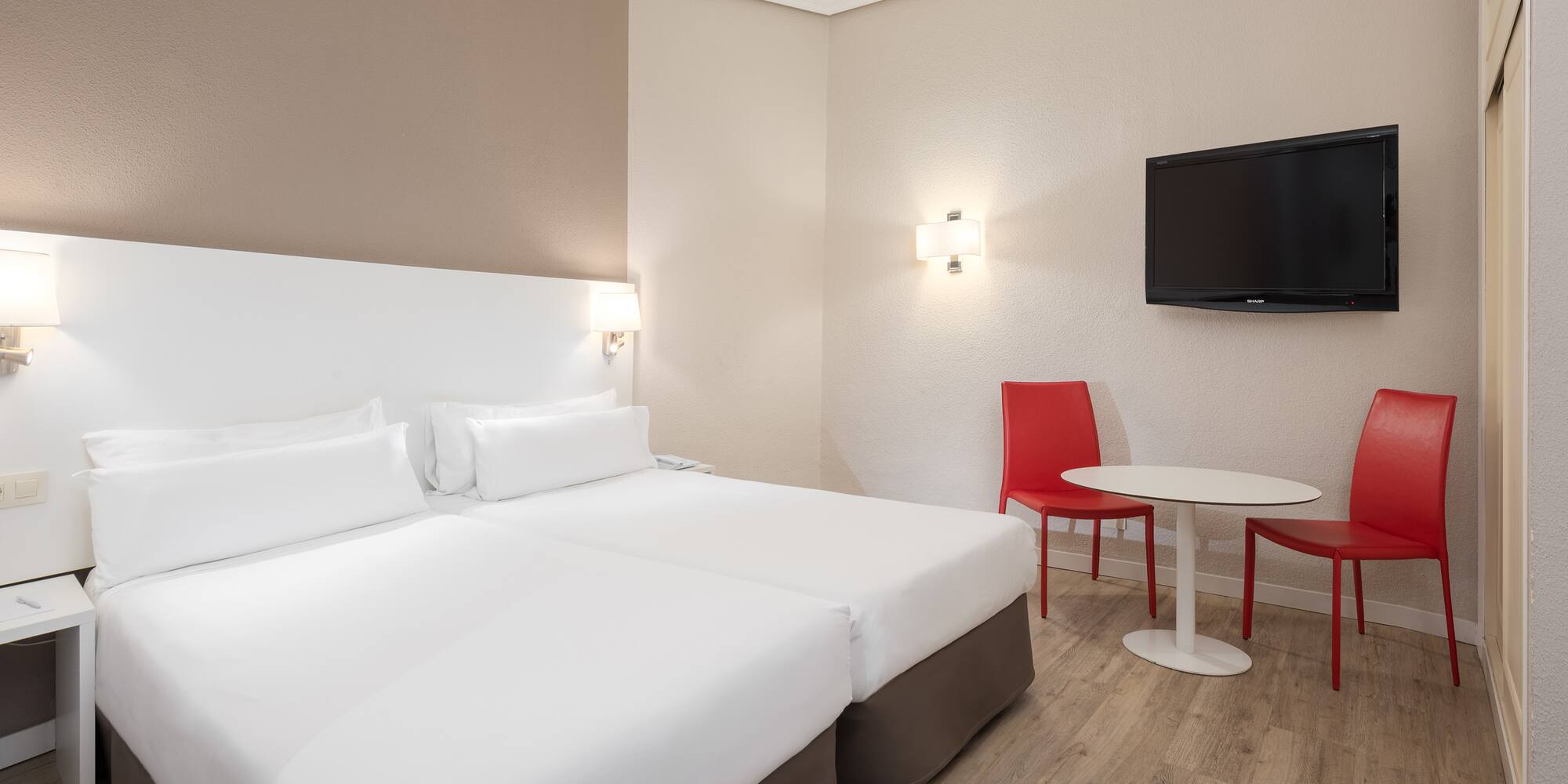 a room with two beds and a table and a tv