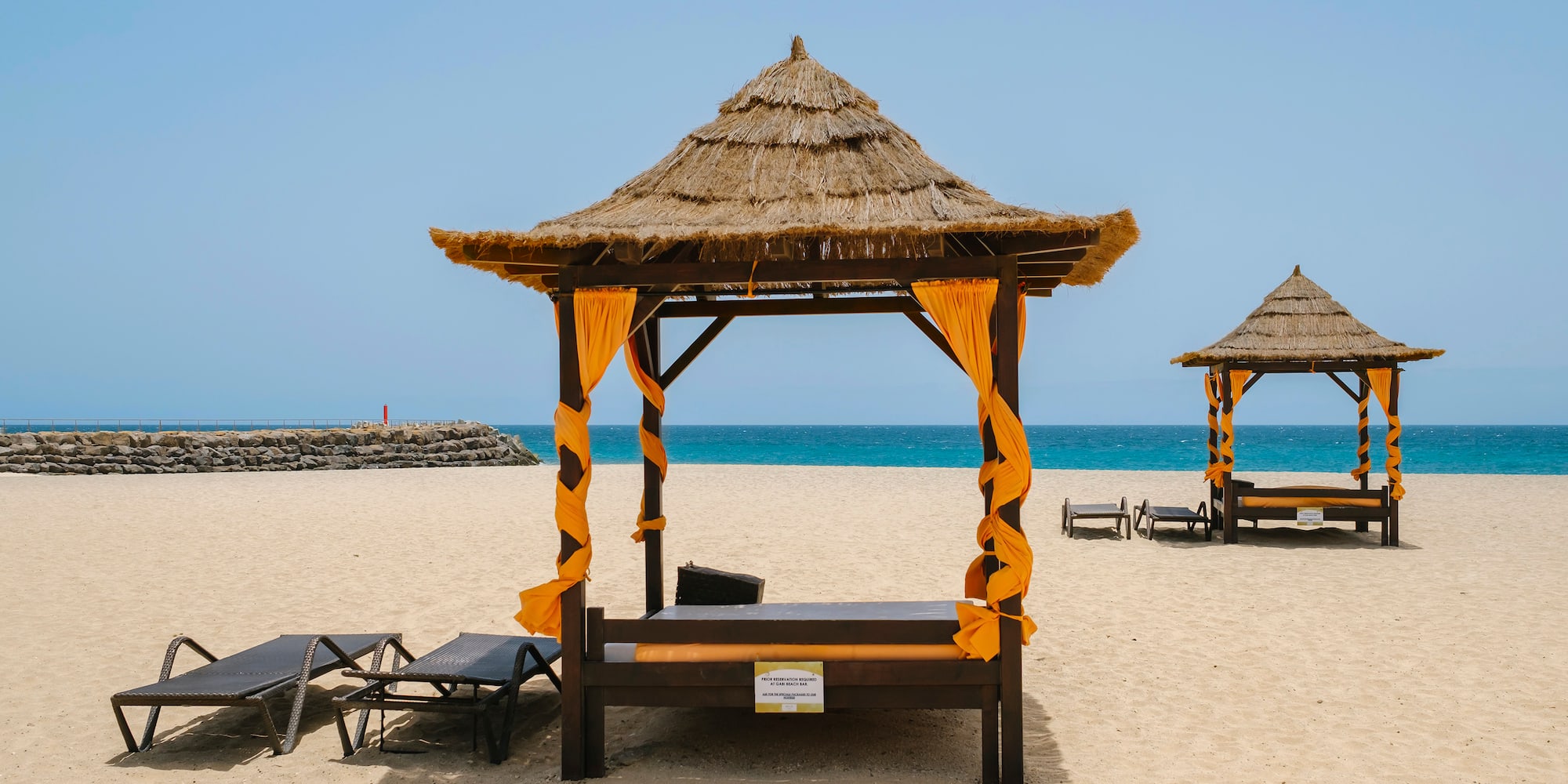 a beach with a hut and chairs