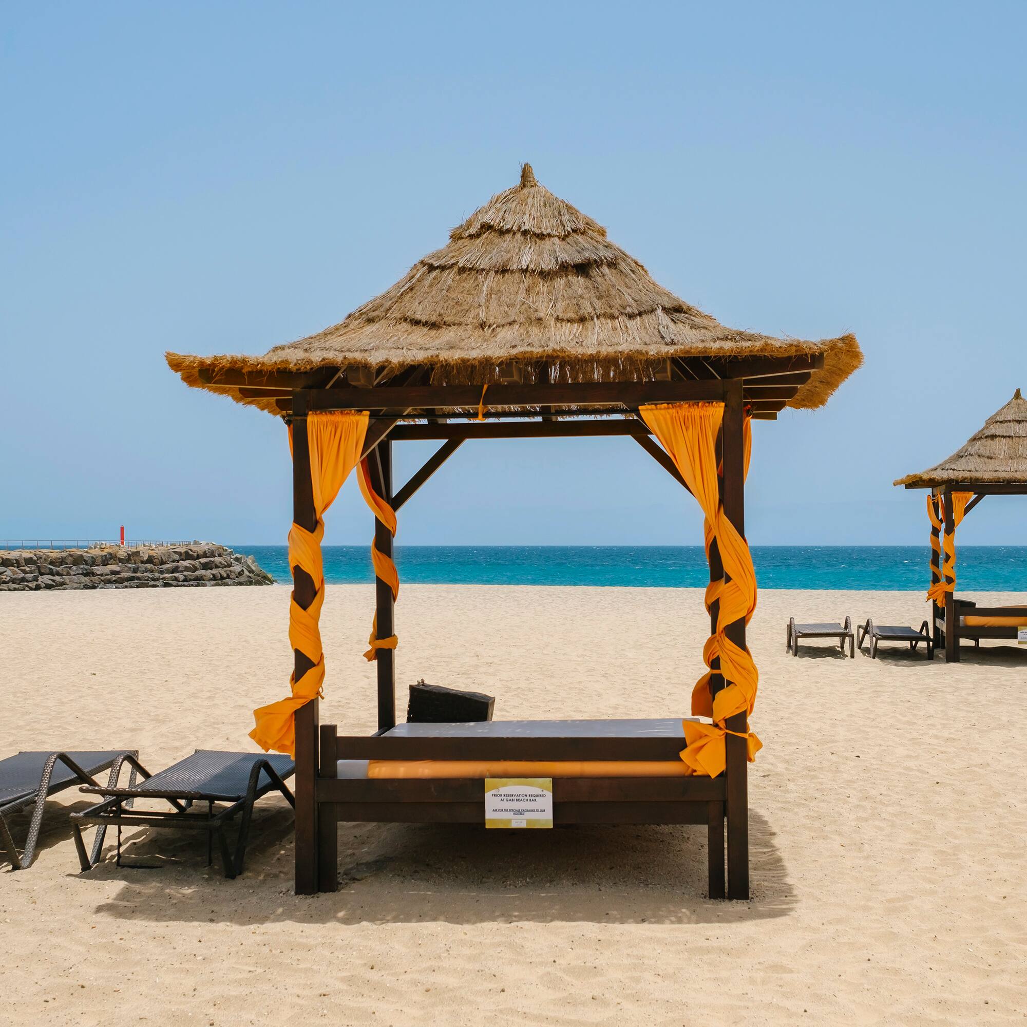 a beach with a hut and chairs
