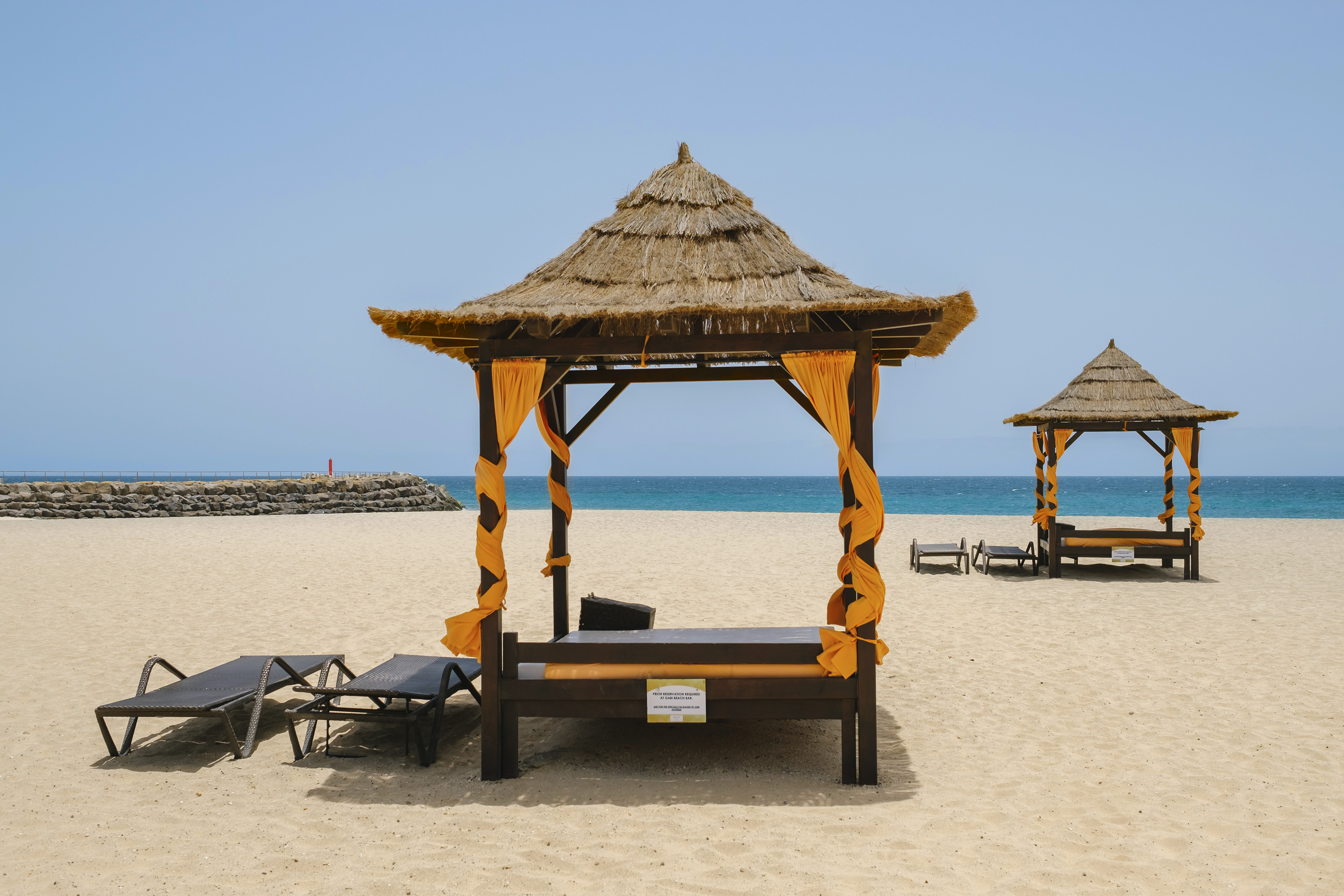 a beach with a hut and chairs