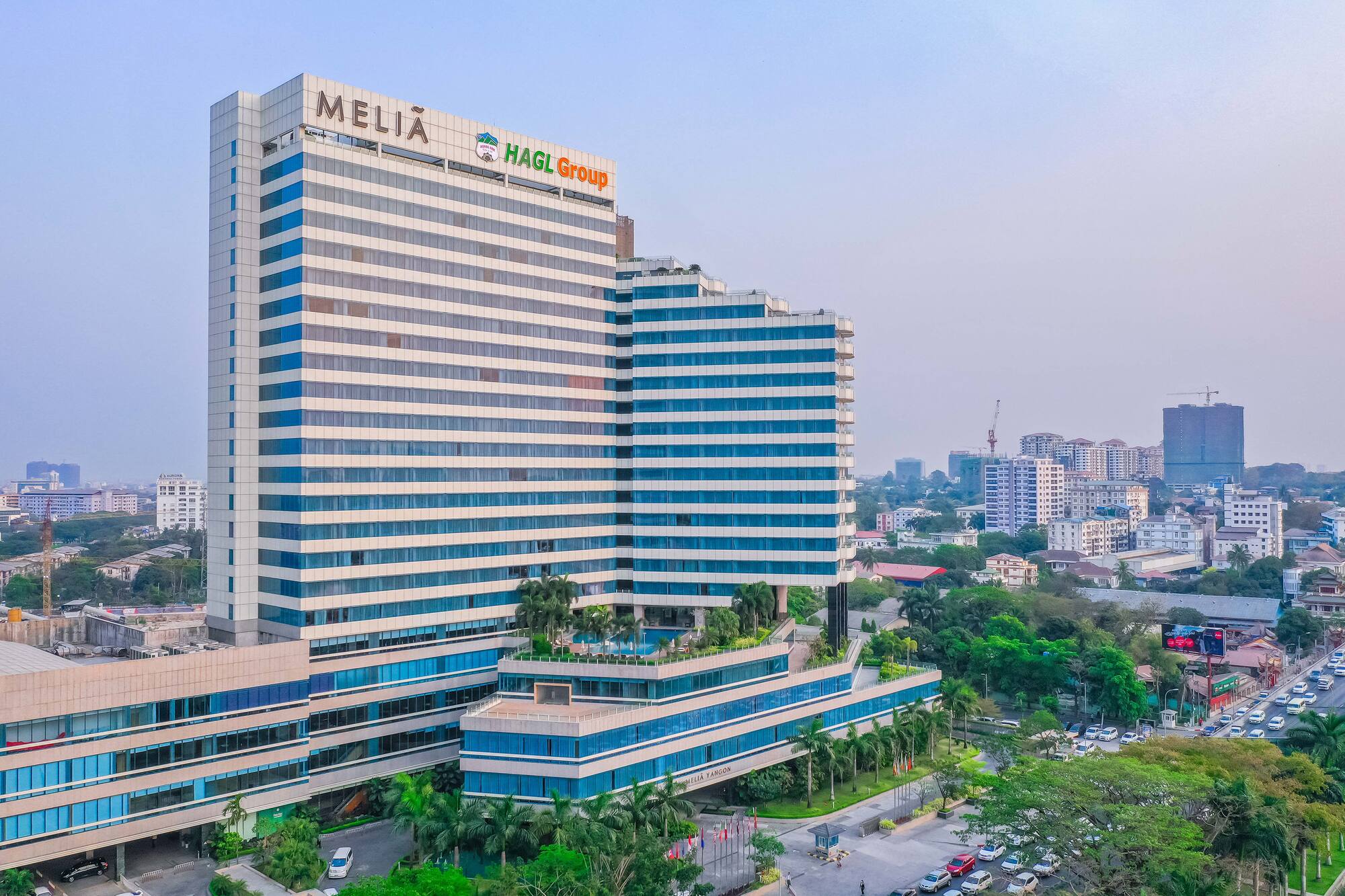 Melia Yangon hotel, modern high-rise with blue windows, green terraced roof.