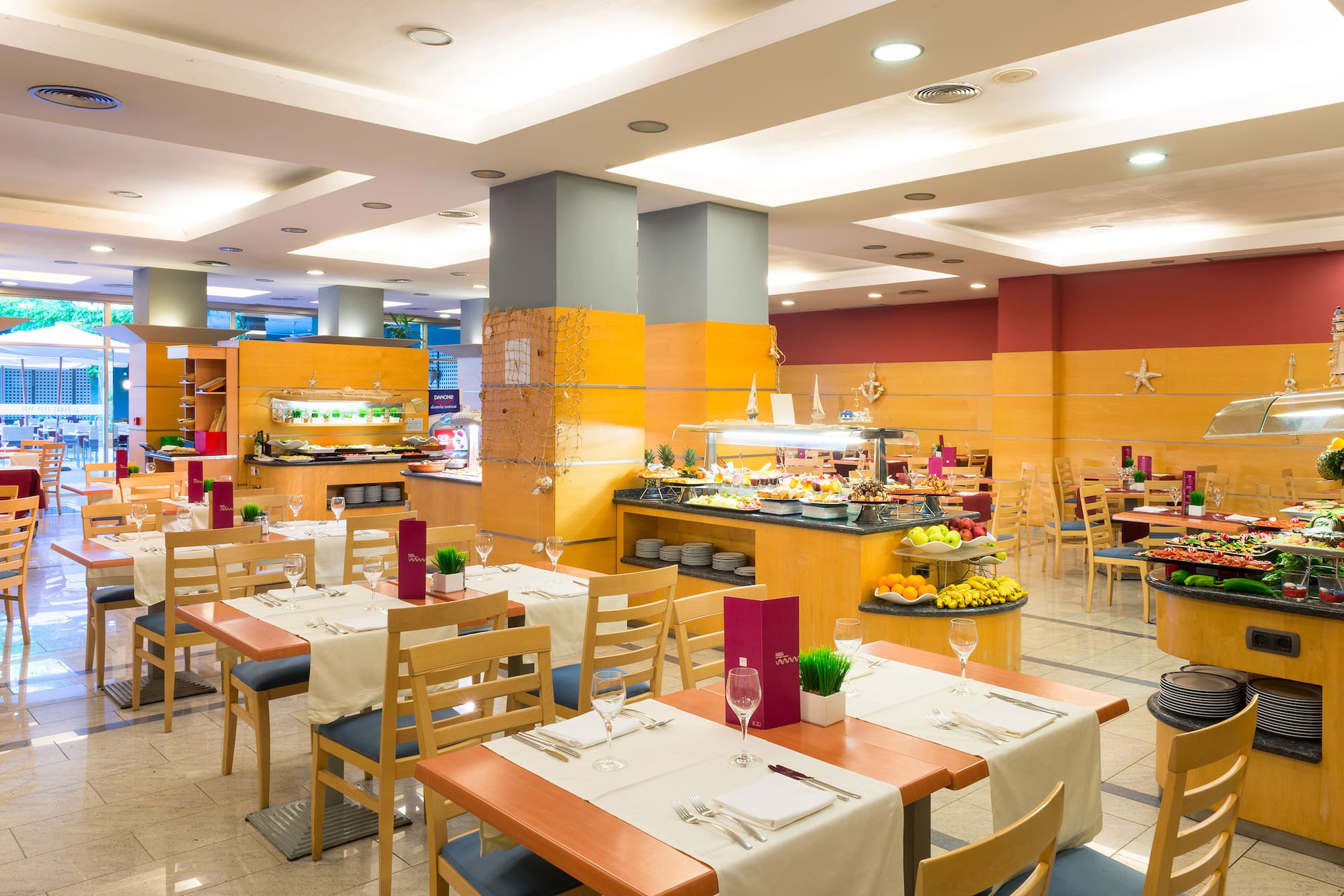 Modern hotel dining room with set tables and a vibrant buffet spread.