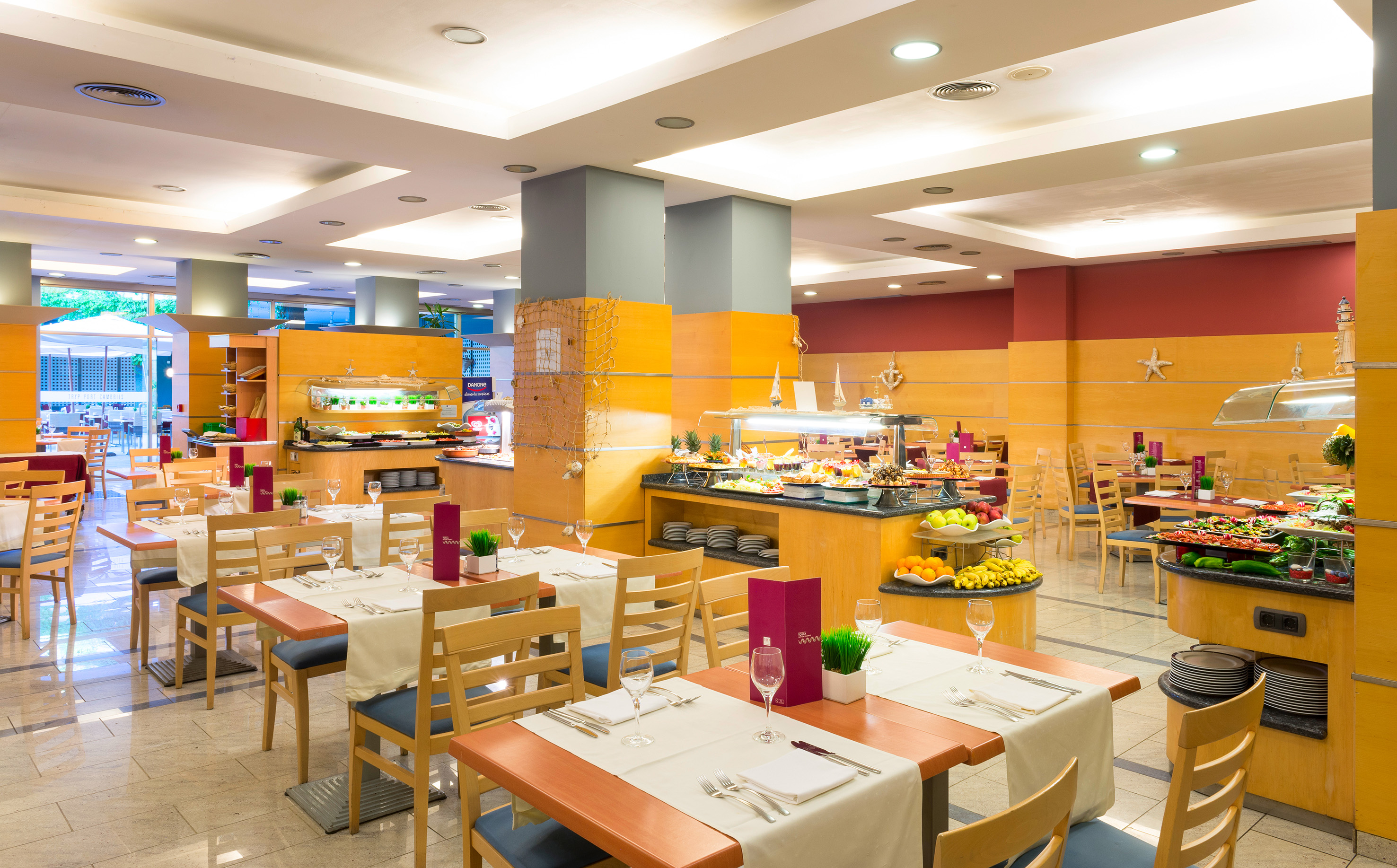 Modern hotel dining room with set tables and a vibrant buffet spread.