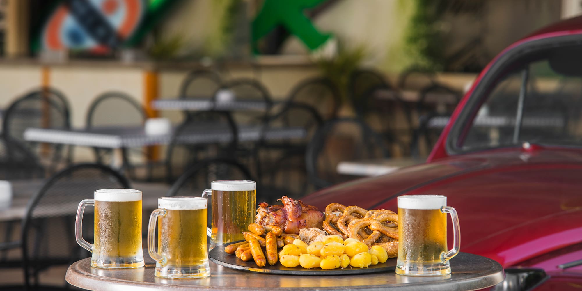 a table with a plate of food and beer mugs