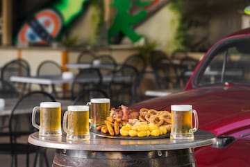a table with a plate of food and beer mugs