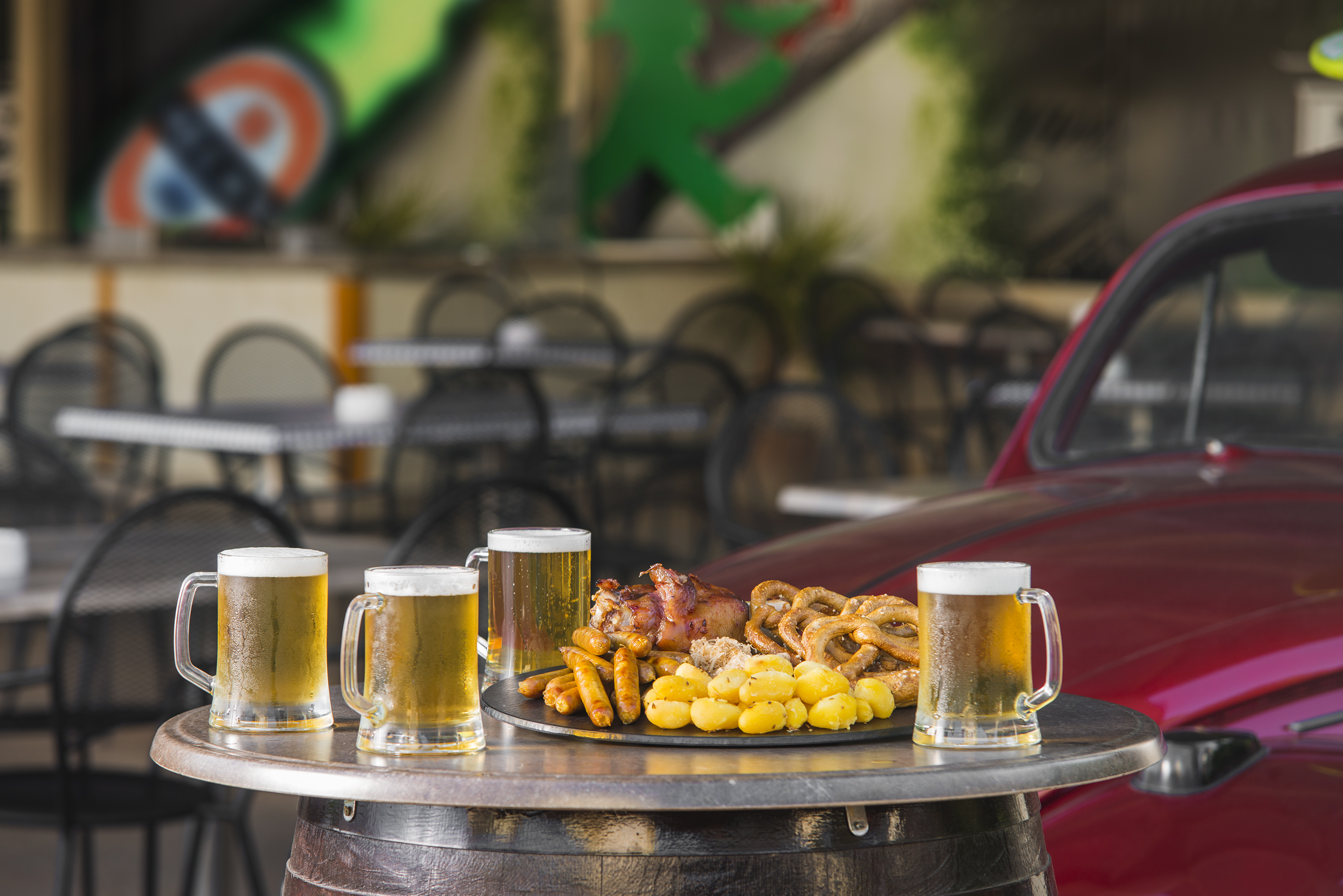 a table with a plate of food and beer mugs