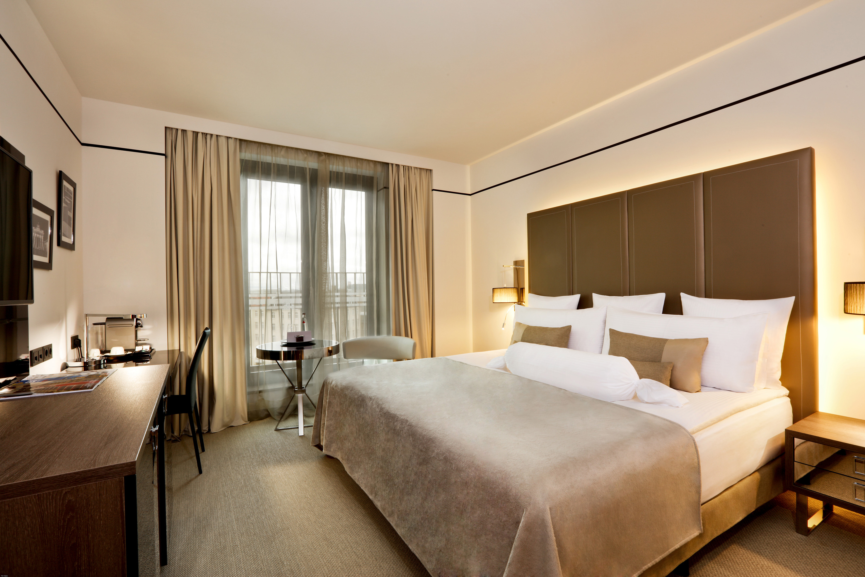 Stylish hotel bedroom with comfortable king bed, work desk, and ambient lighting.