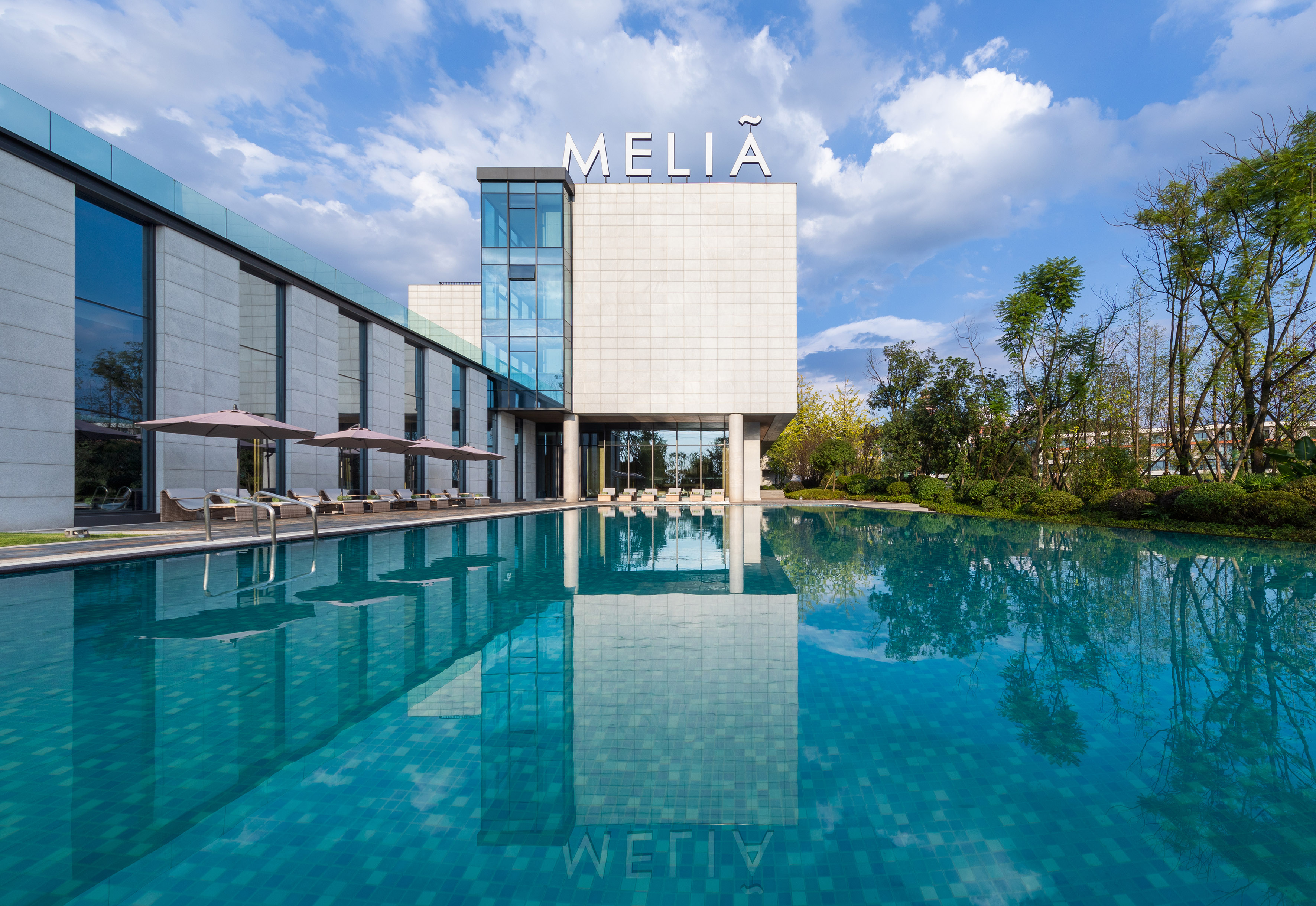 Modern Melia hotel building reflected in its large outdoor swimming pool.