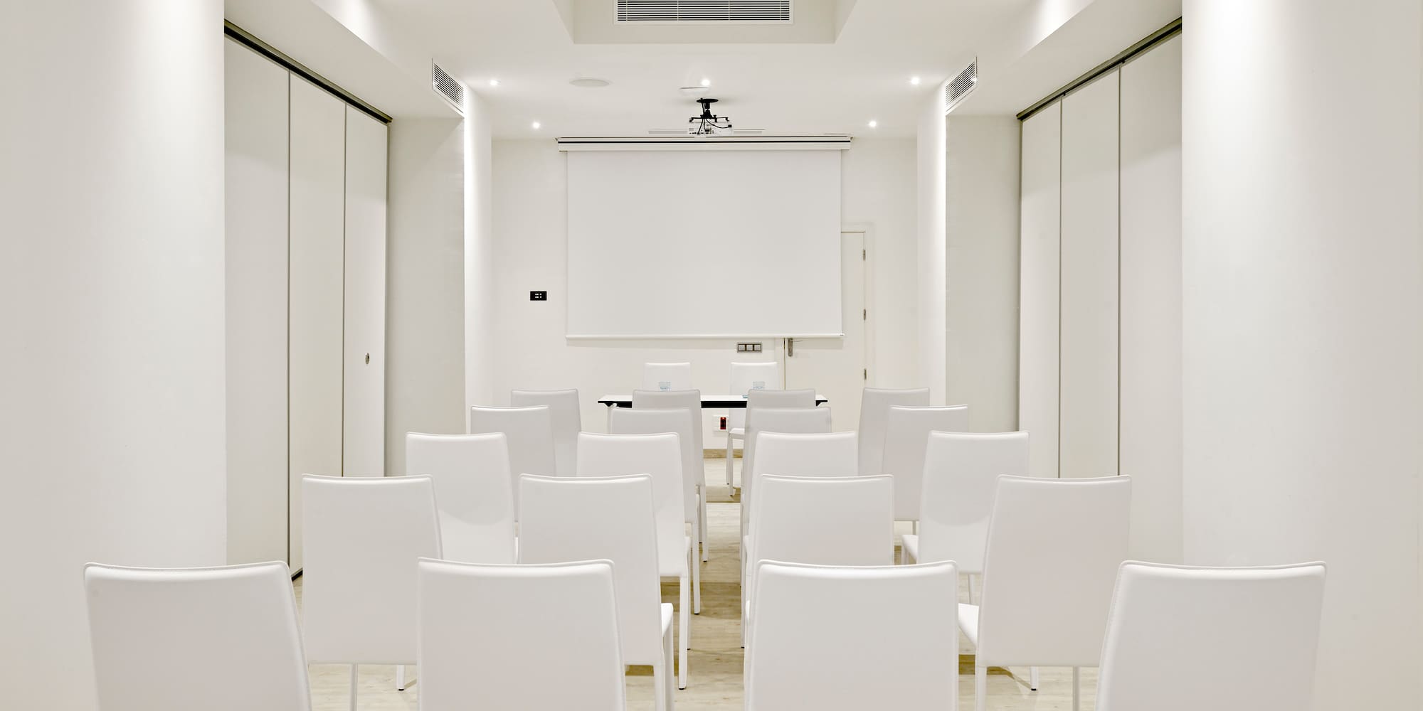 a room with white chairs and a projector screen