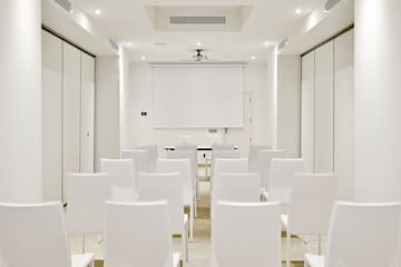 a room with white chairs and a projector screen